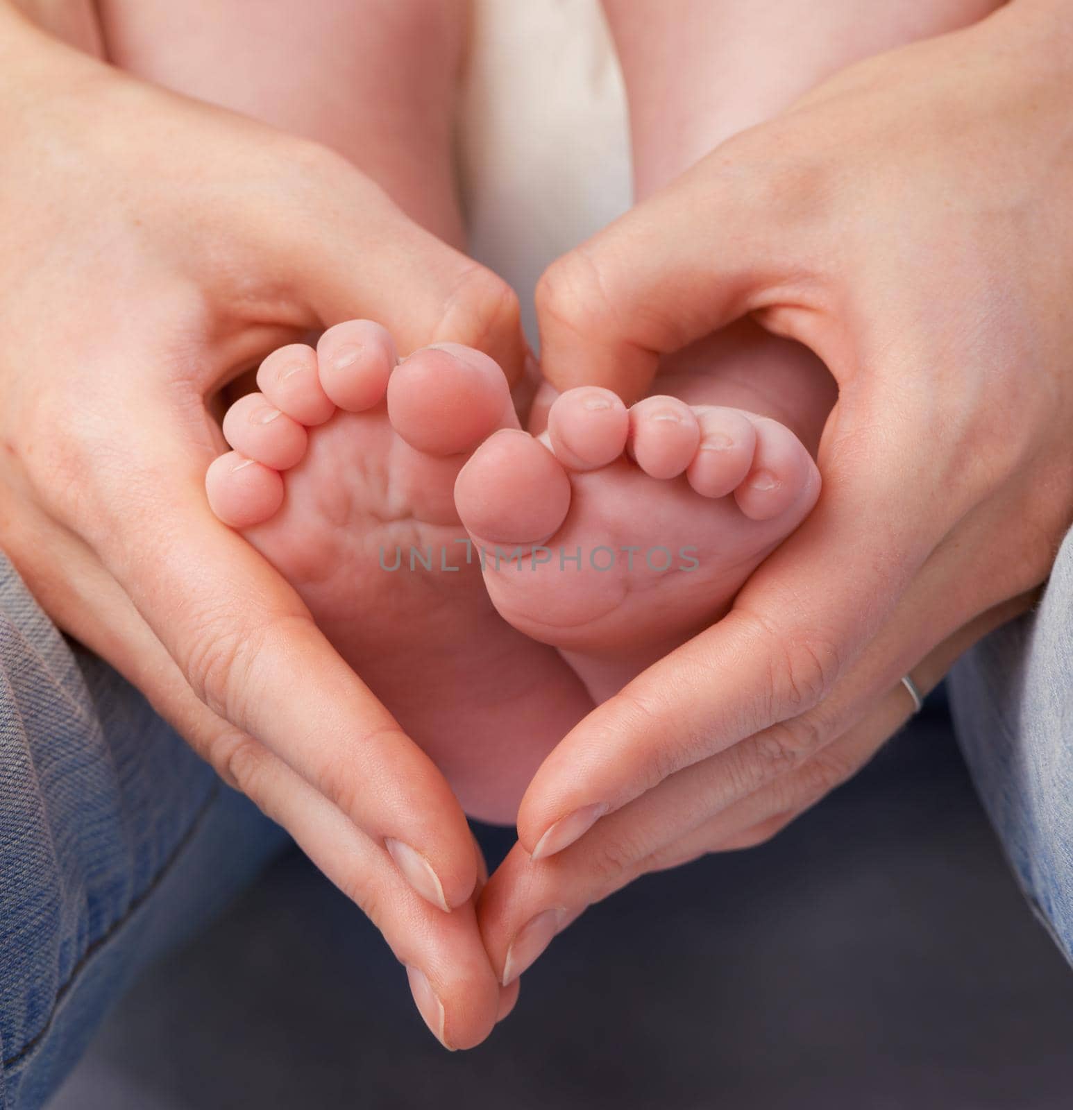 Loving the little things. Cropped shot of a mothers hands making a heart shape around her babys feet. by YuriArcurs