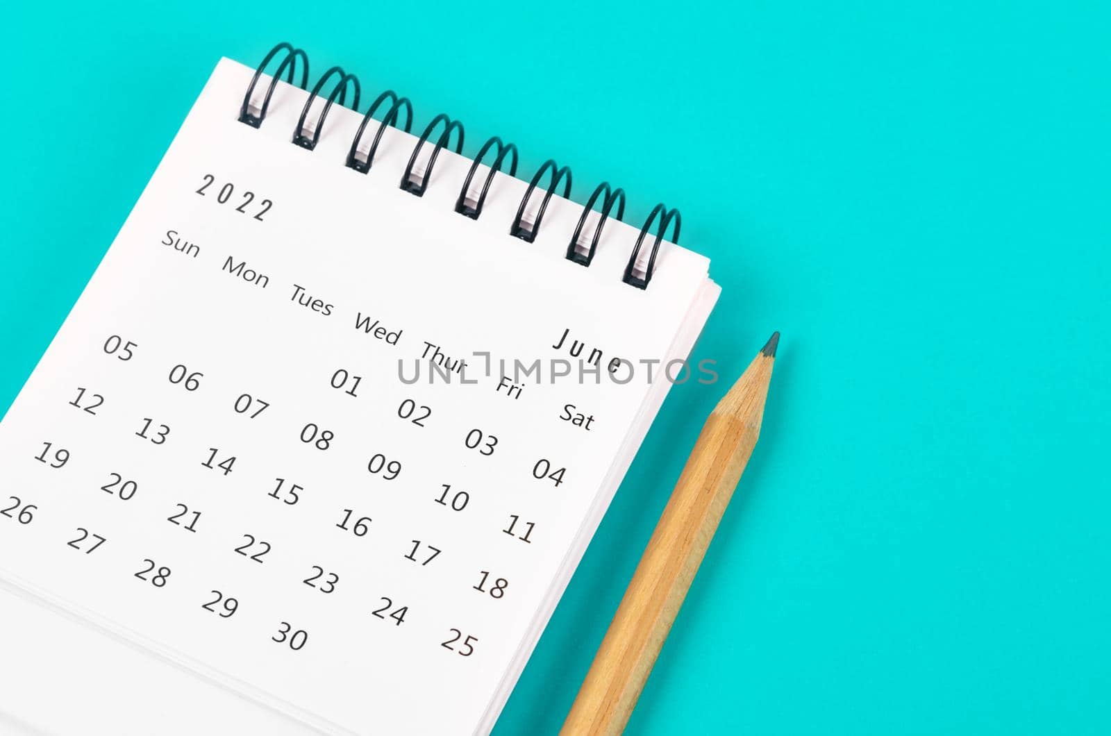 The June 2022 desk calendar with wooden pencil on light blue background.