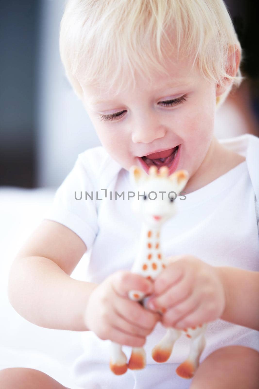 Learning about animals. Shot of a young baby playing with a toy giraffe. by YuriArcurs