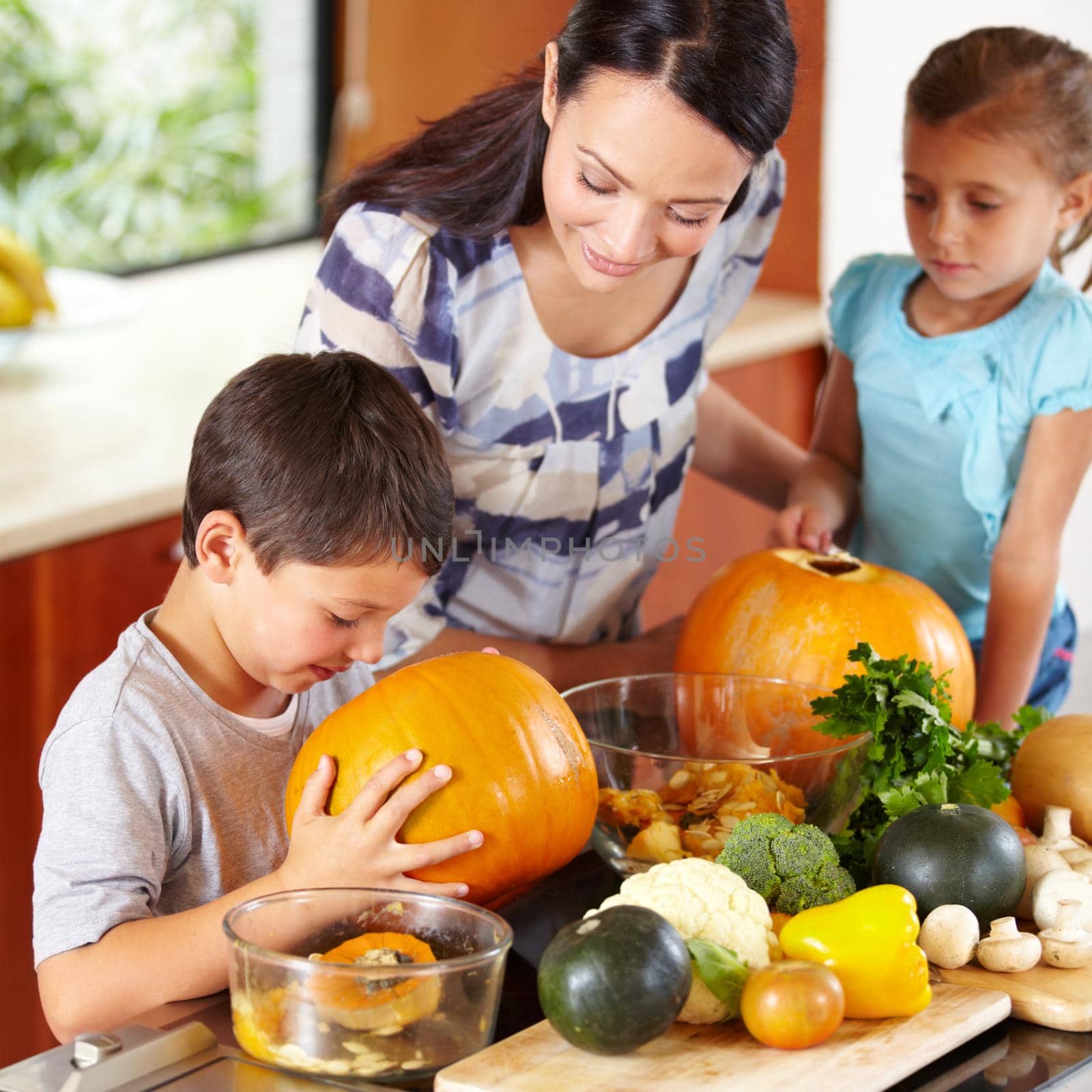 I think its ready. Shot of a mother helping her children carve pumpkins for halloween. by YuriArcurs