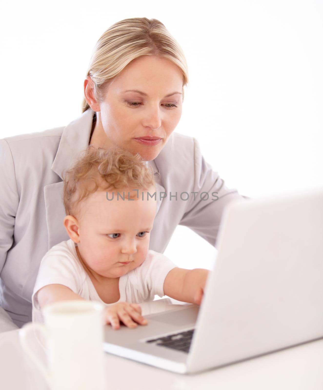 A businesswoman working on her laptop with her baby on her lap.