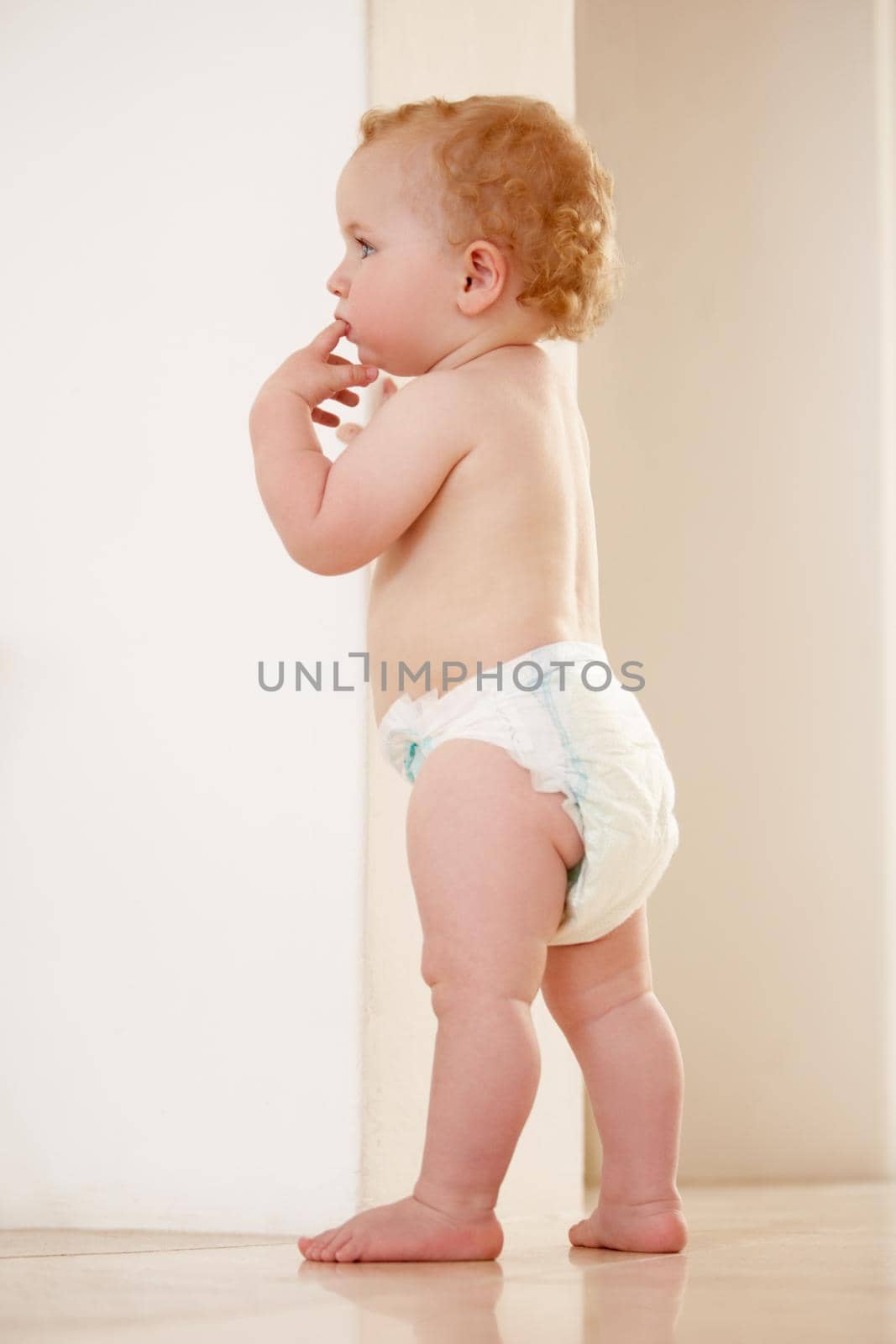 Adorable baby boy standing by himself and looking away.
