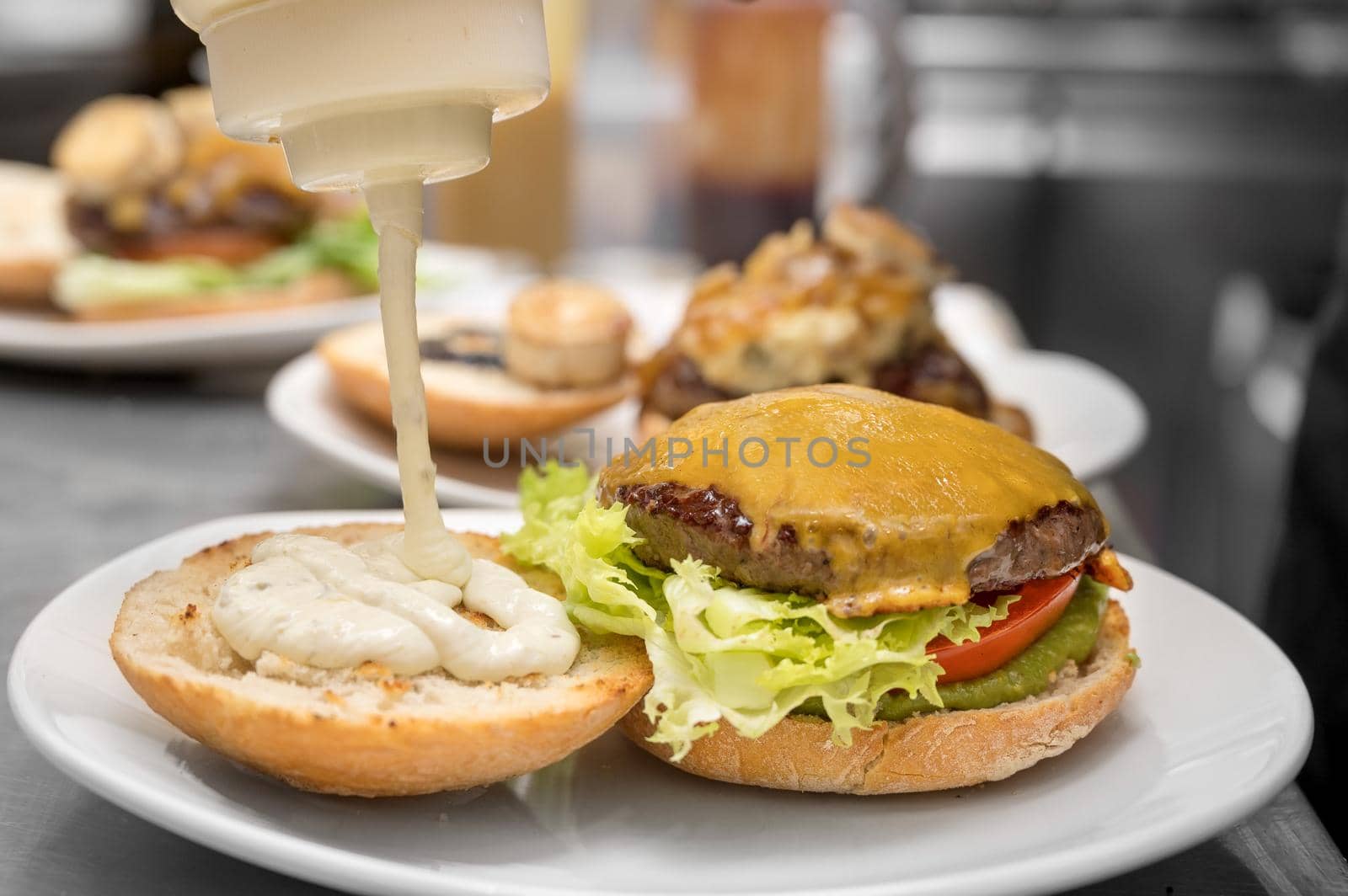Chef cooking burger,close-up, making sandwich, fast food concept, recipe of preparing homemade hamburger with vegetables. by HERRAEZ