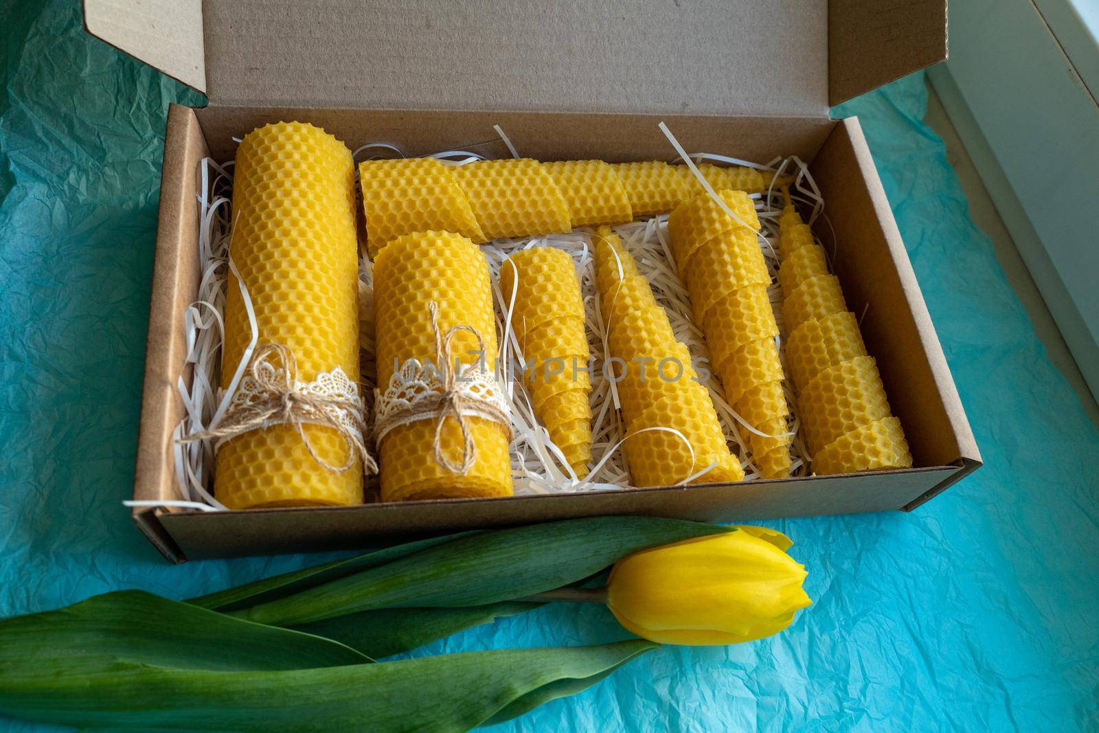 Seven beeswax candles in a box. The candles are decorated with lace and tied with a jute rope