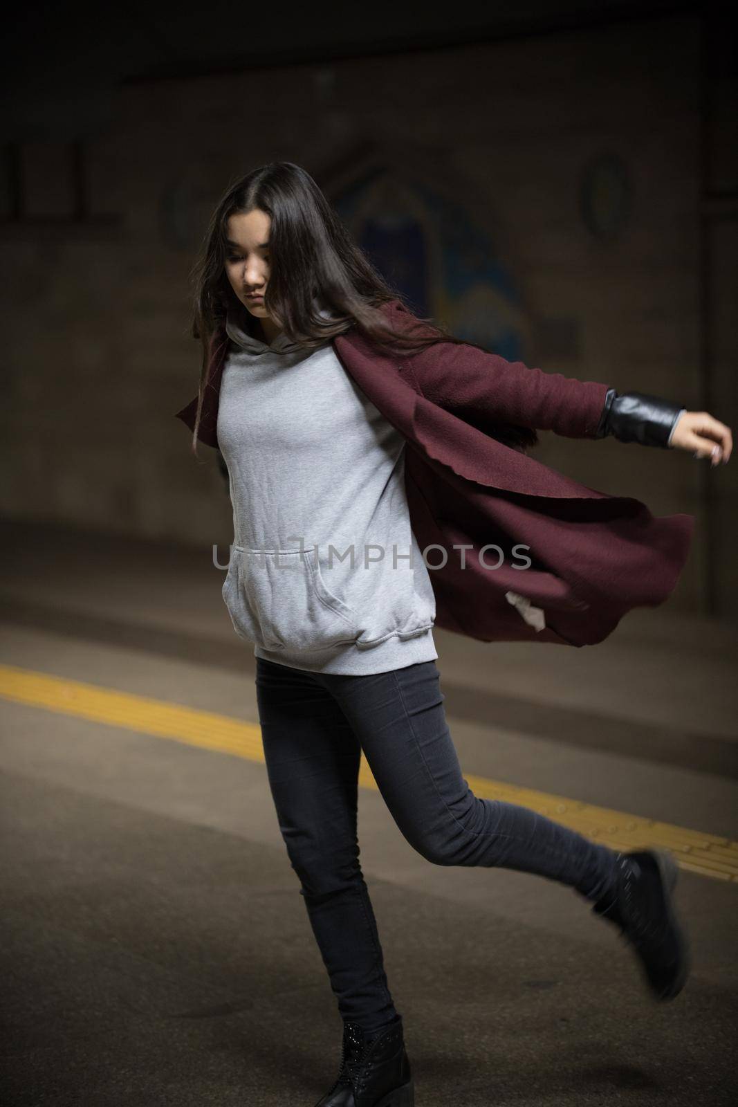 Photo of young woman in night subway walking forward. Full body