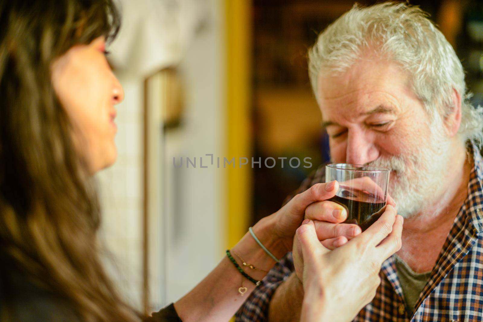 caucasian man drinking wine and getting drunk harassing young hispanic woman wife - alcoholism and domestic violence concept by verbano