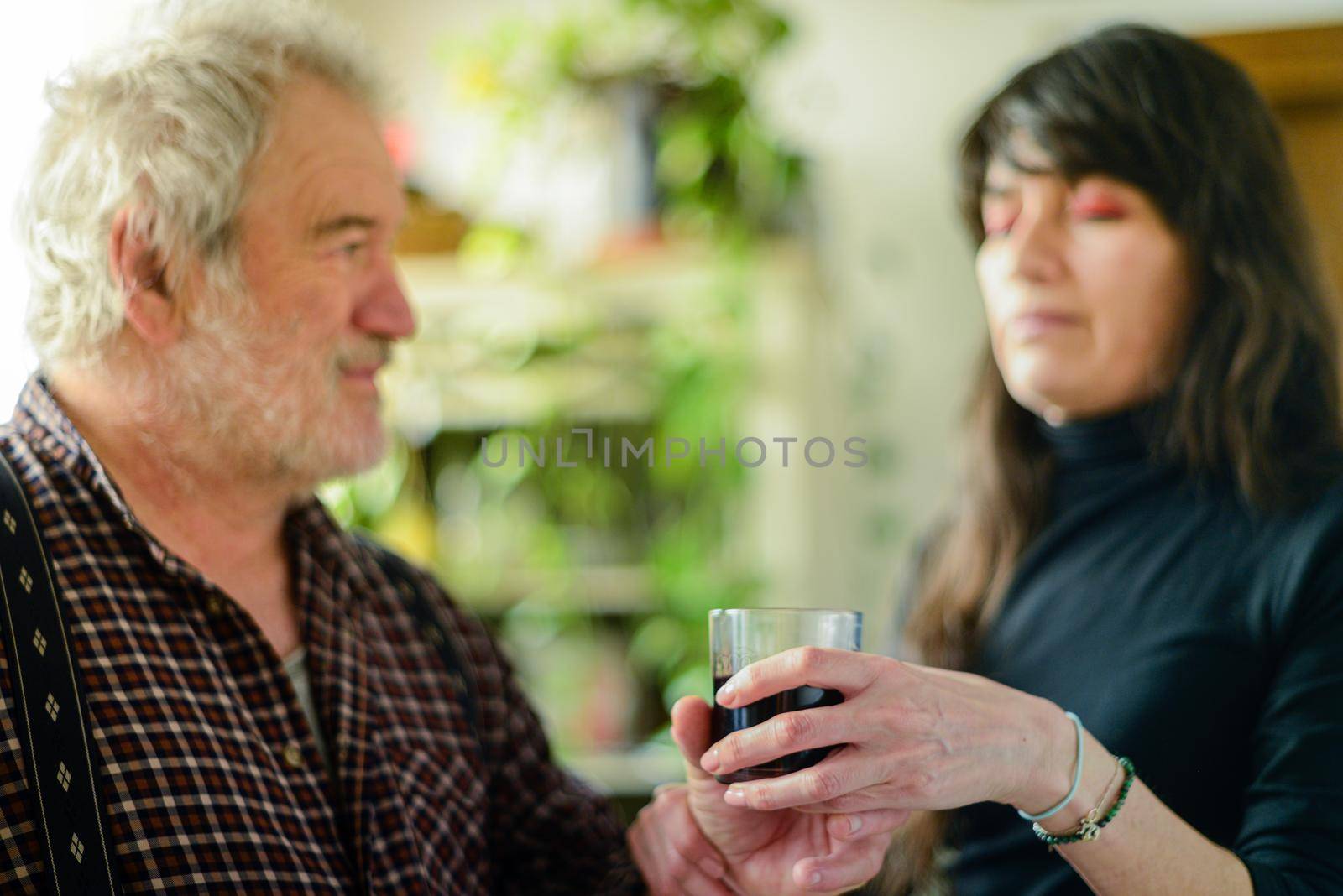 caucasian man drinking wine and getting drunk harassing young hispanic woman wife - alcoholism and domestic violence concept by verbano