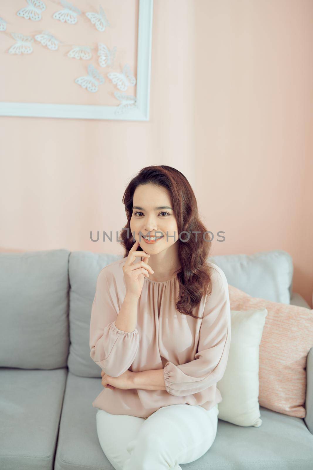 Portrait of smiling beauty sitting on sofa by makidotvn