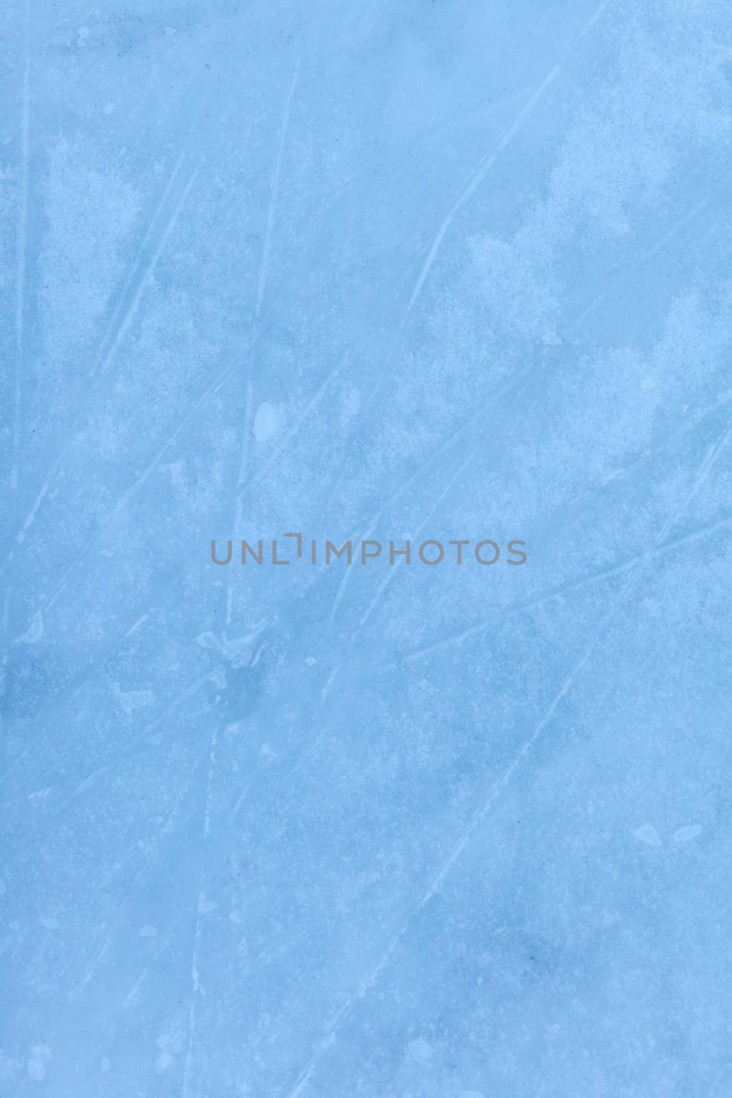 Empty ice rink with skate marks after the session outdoor. skating ice rink texture covered with snow in daylight. Close up of blue ice rink floor, copy space