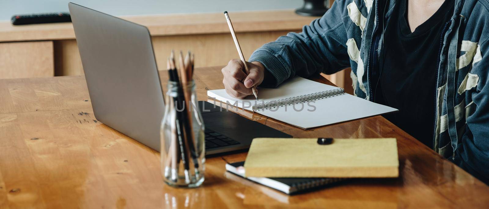 Cropped photo of woman writing making list taking notes in notepad working or learning on laptop indoors- educational course or training, seminar, education online concept by nateemee