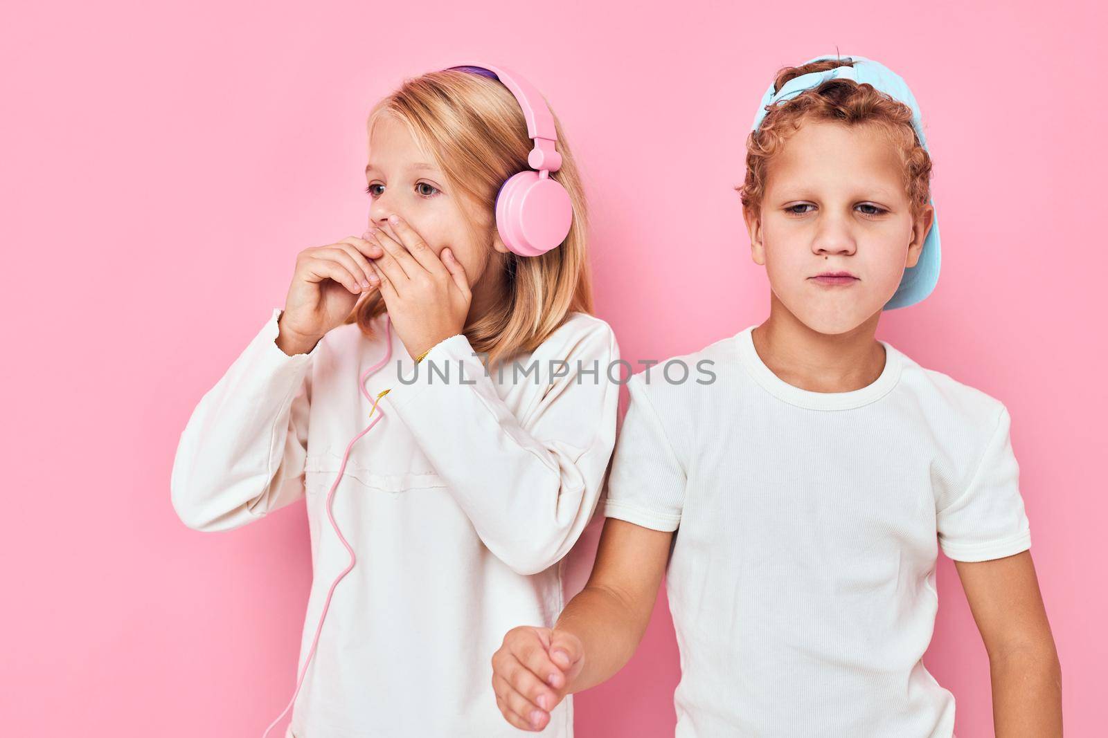 girl with headphones next to boy standing side by side posing fashion isolated background. High quality photo