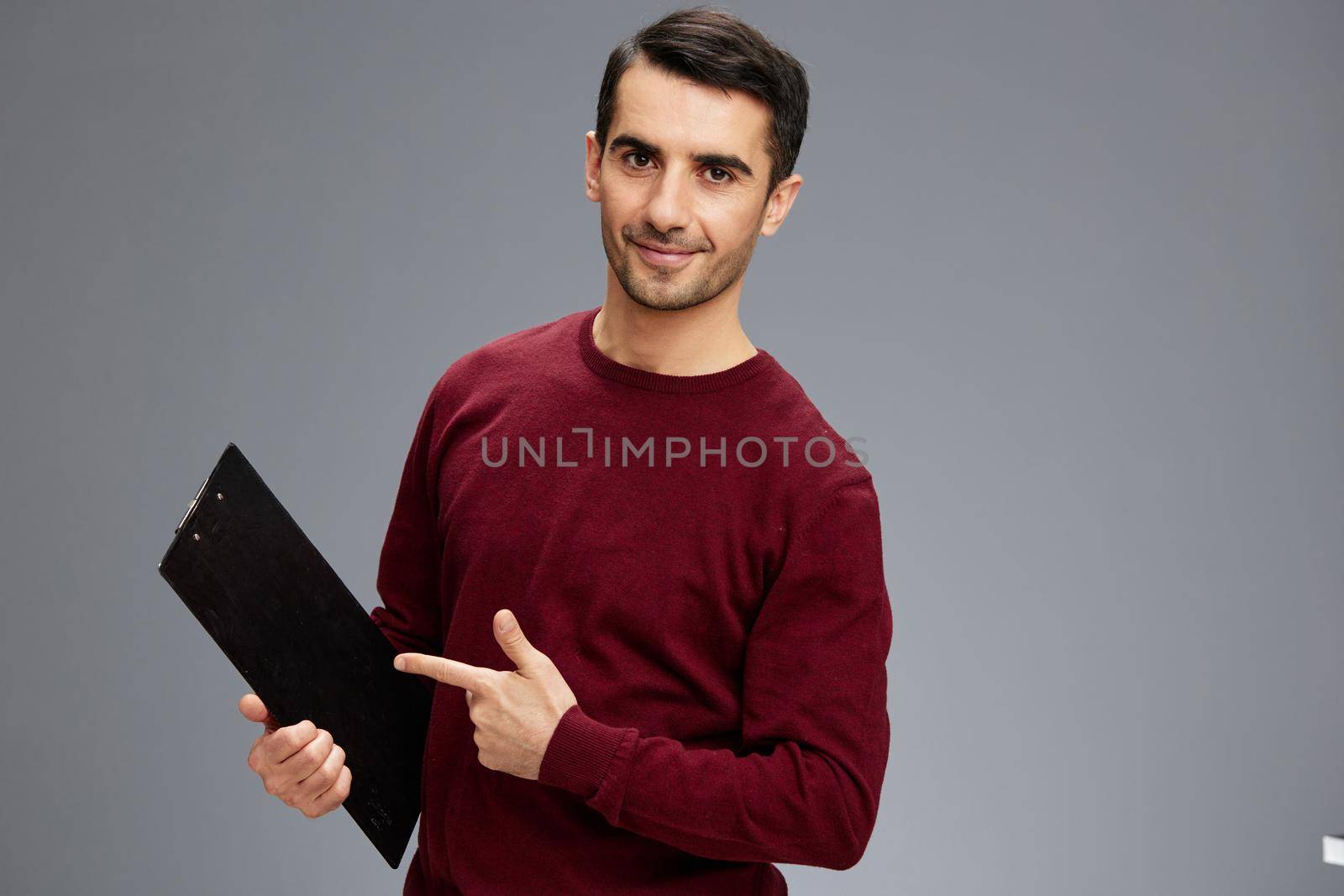 manager with a smile points a finger at a notepad in a sweater posing documentation emotions isolated background. High quality photo