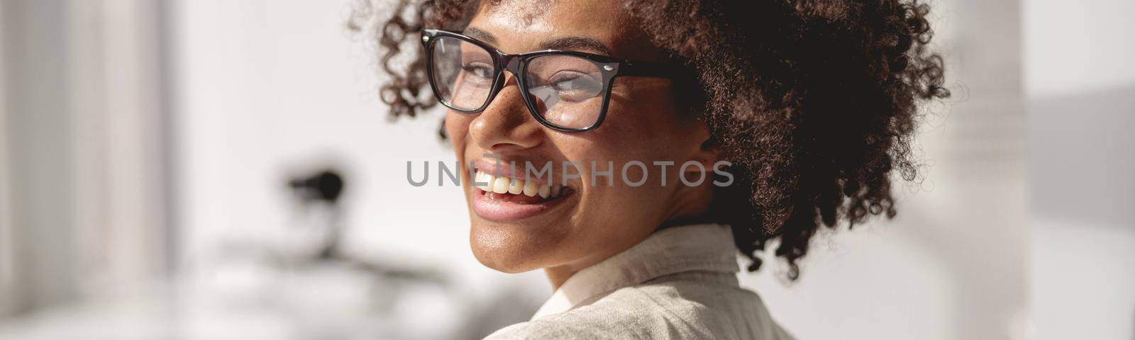 Close up of Afro American worker wearing glasses and using smartphone in the office