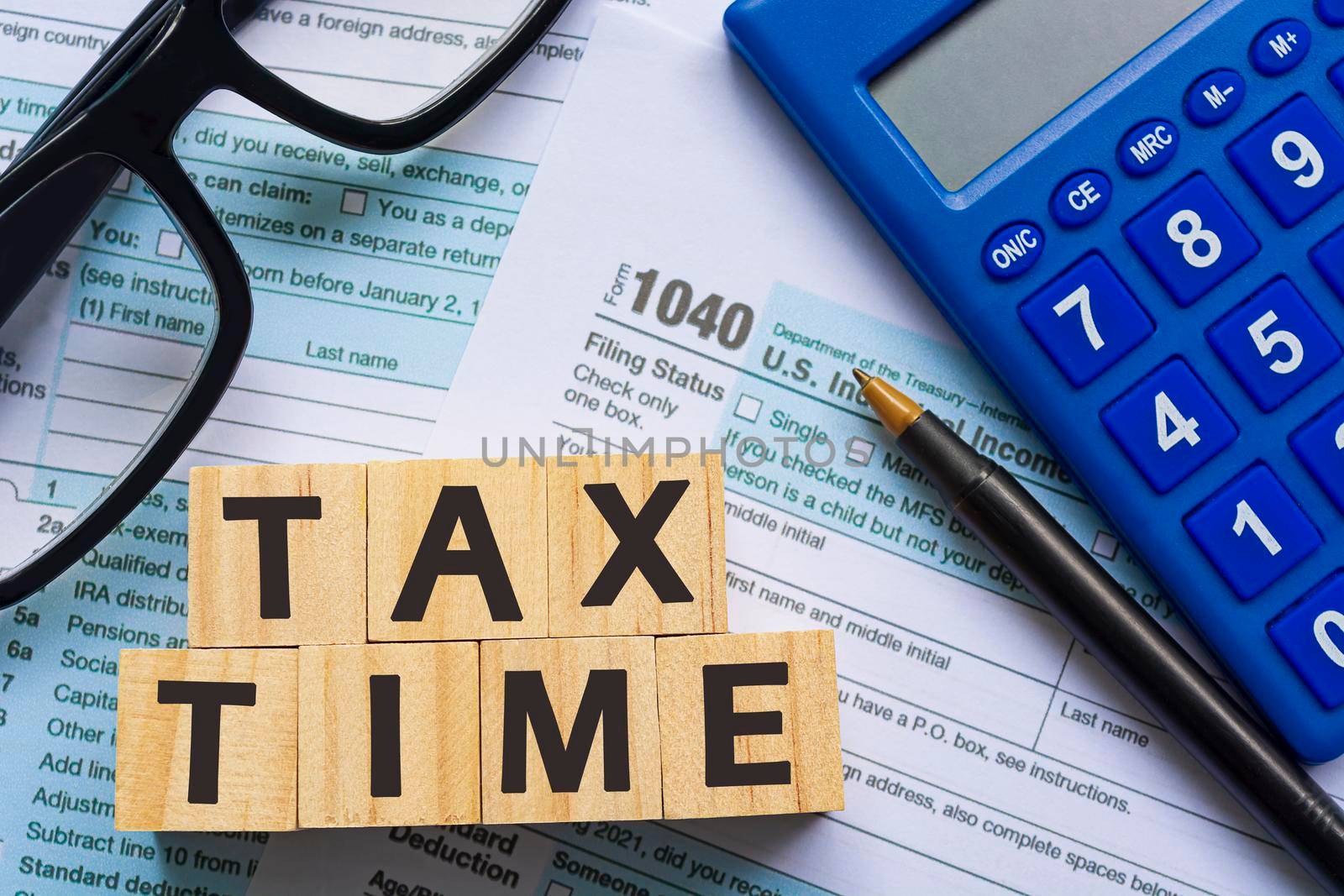 Text on Alphabet wooden block cube with Tax forms 1040. U.S Individual Income Tax Return on a desk. Business and tax concept. Time to pay tax in year.