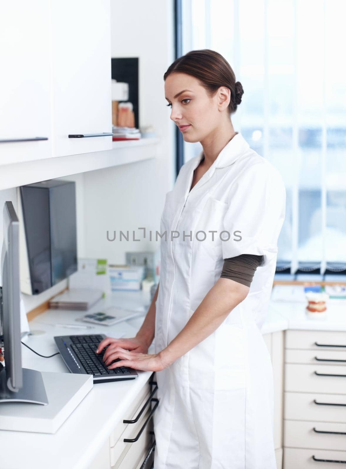 Portrait of female dentist working on computer in office.