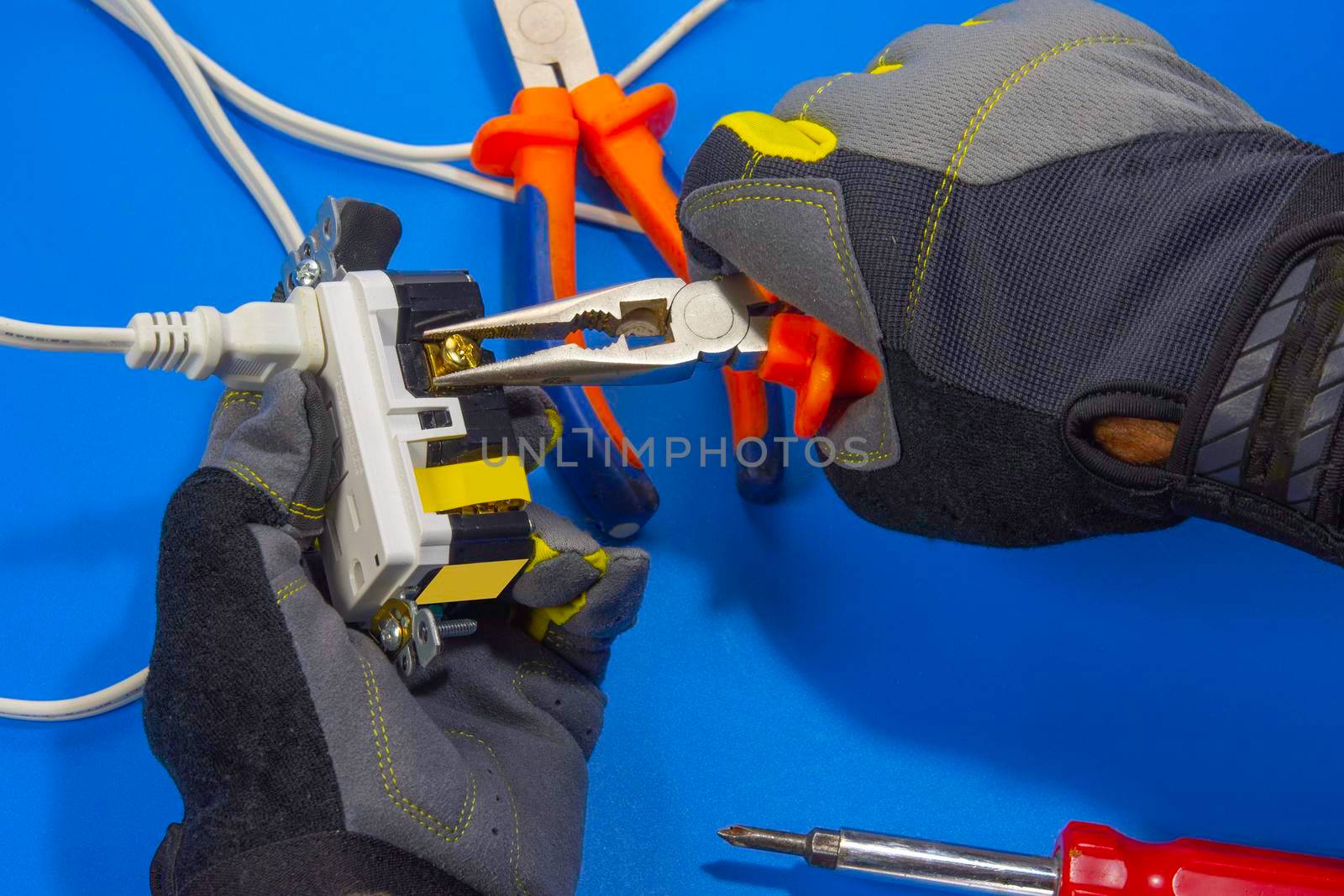 Electrician adjusts a screw on an electrical outlet by ben44