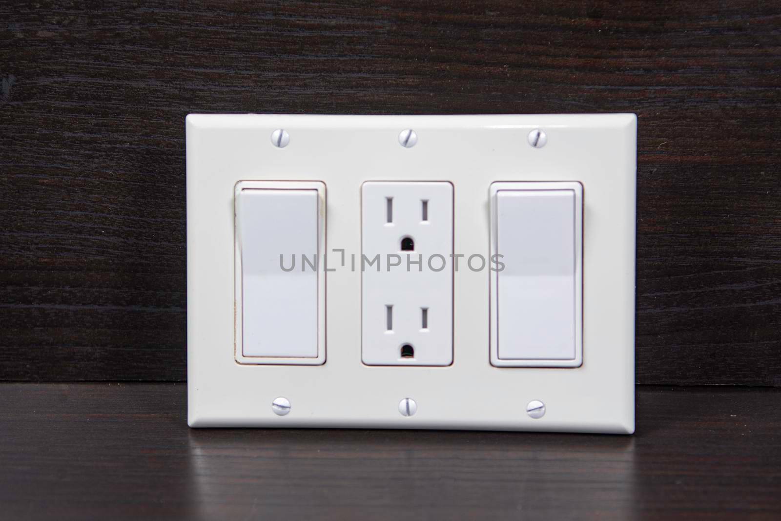 Two switches and one socket against a wooden background by ben44