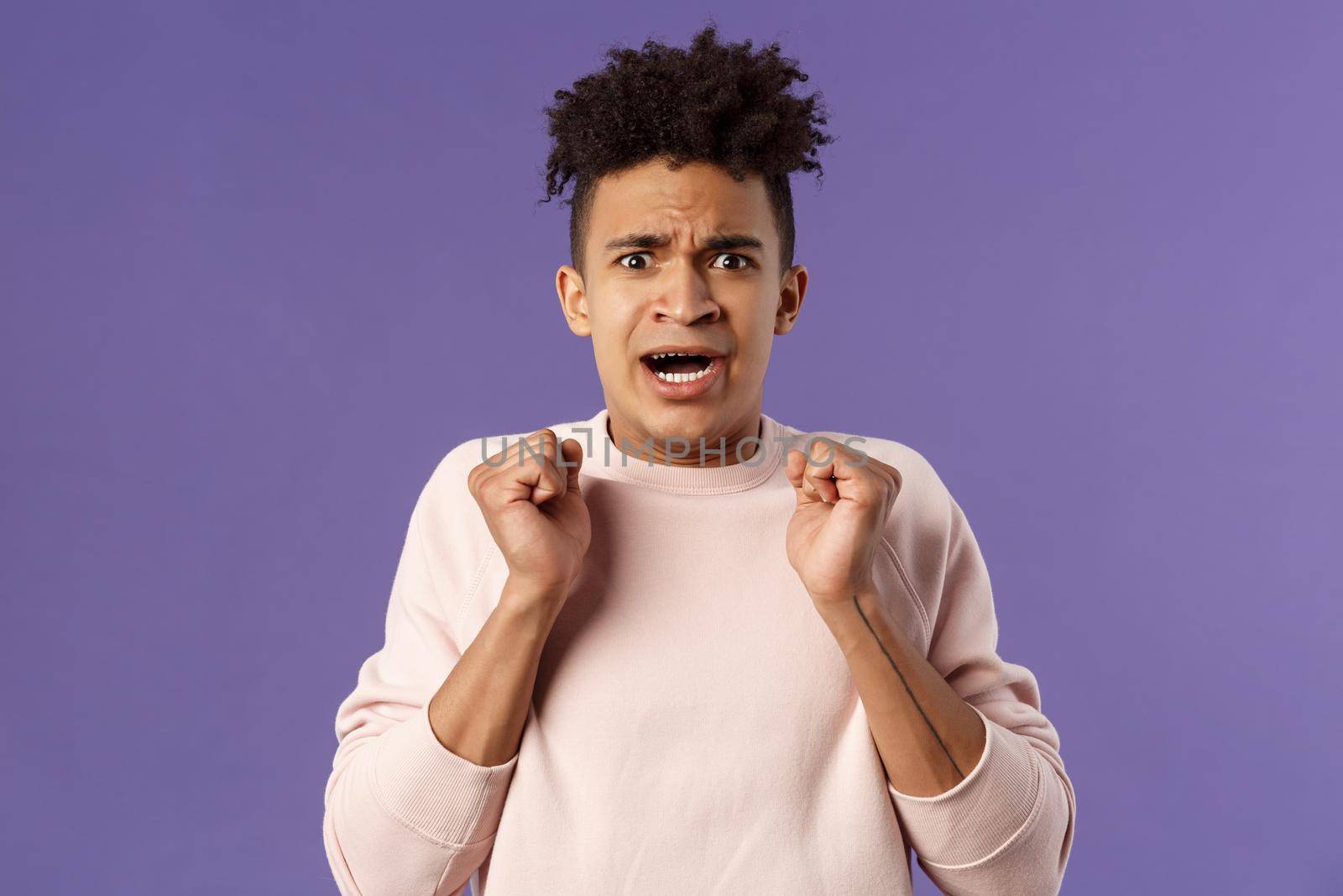 Close-up portrait of worried, anxious funny hispanic man jumping from fear, gasping look concerned, starting to panic before important meeting, standing purple background afraid and nervous.