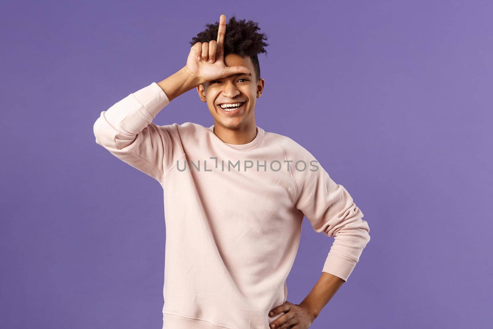 Portrait of charismatic happy, boastful young hispanic guy mocking friend for losing to him, showing loser gesture over forehead and laughing over defeated person, stand purple background by Benzoix