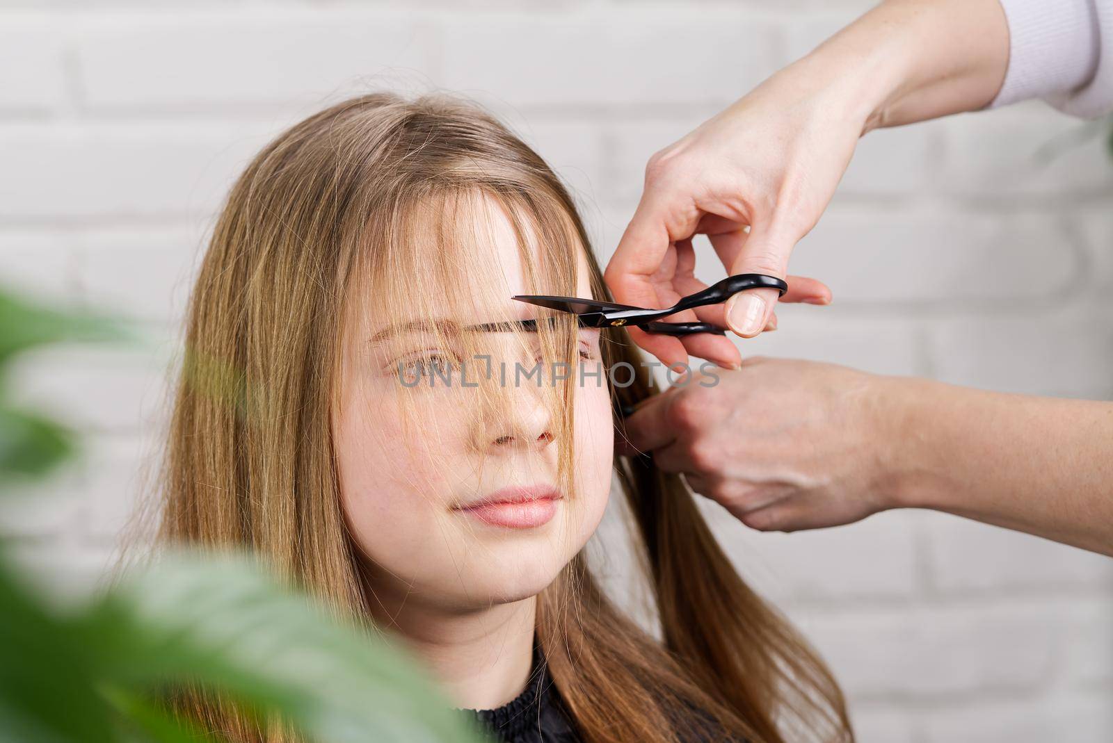 Hairdresser making a hair to cute girl in hair salon. Young girl at hairdresser by PhotoTime