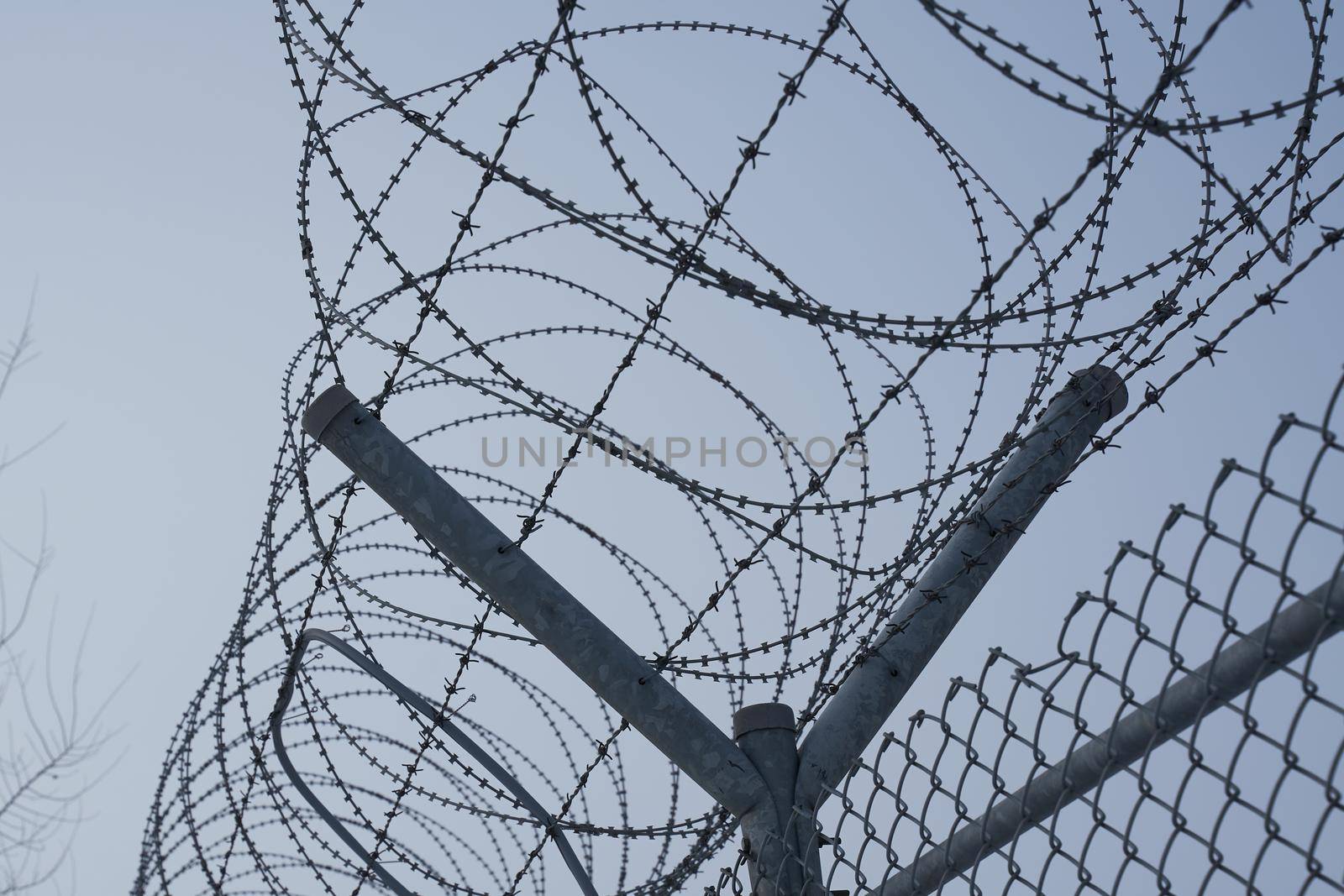 Prison fence against blue sky closeup. Barbed wire. Restricted area. Classified state zone.