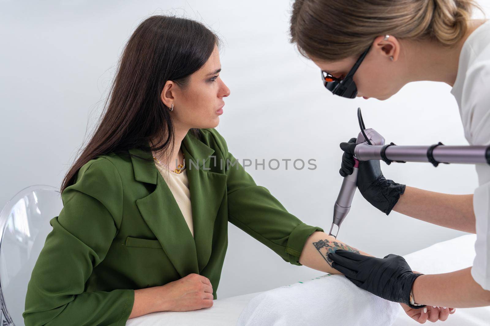 Cosmetologist removing tattoo with laser device female hand. Concept of erasing tattoos as expensive procedure in cosmetology clinic