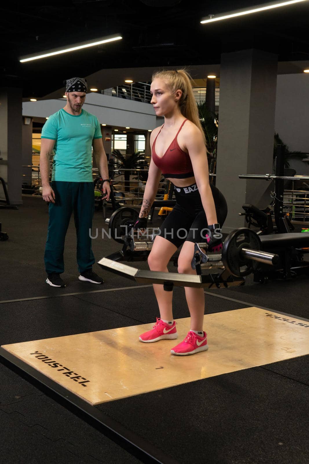 RUSSIA, MOSCOW - FEB 11, 2022: Instructor and client girl deadlift blonde trap bar personal exercise, for lifestyle lifting for person and sport strength, concept couple. Working female bodybuilding, training by 89167702191