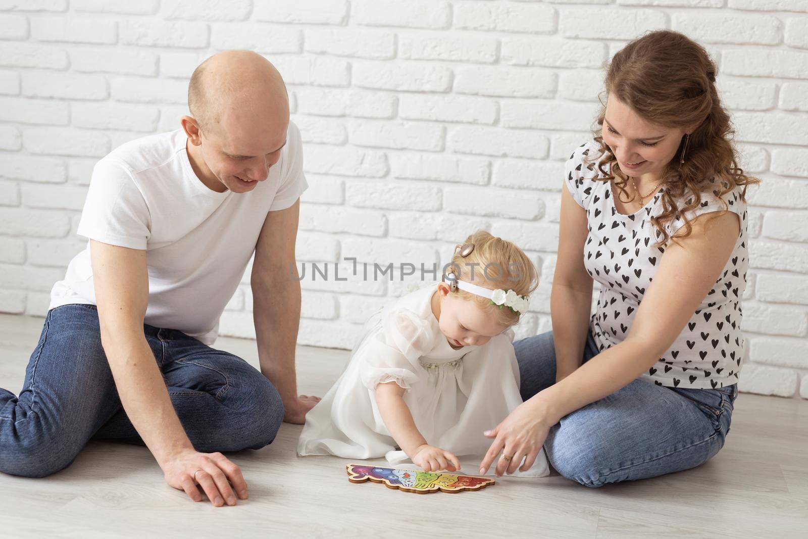 Baby child with hearing aids and cochlear implants plays with parents on floor. Deaf and rehabilitation concept by Satura86