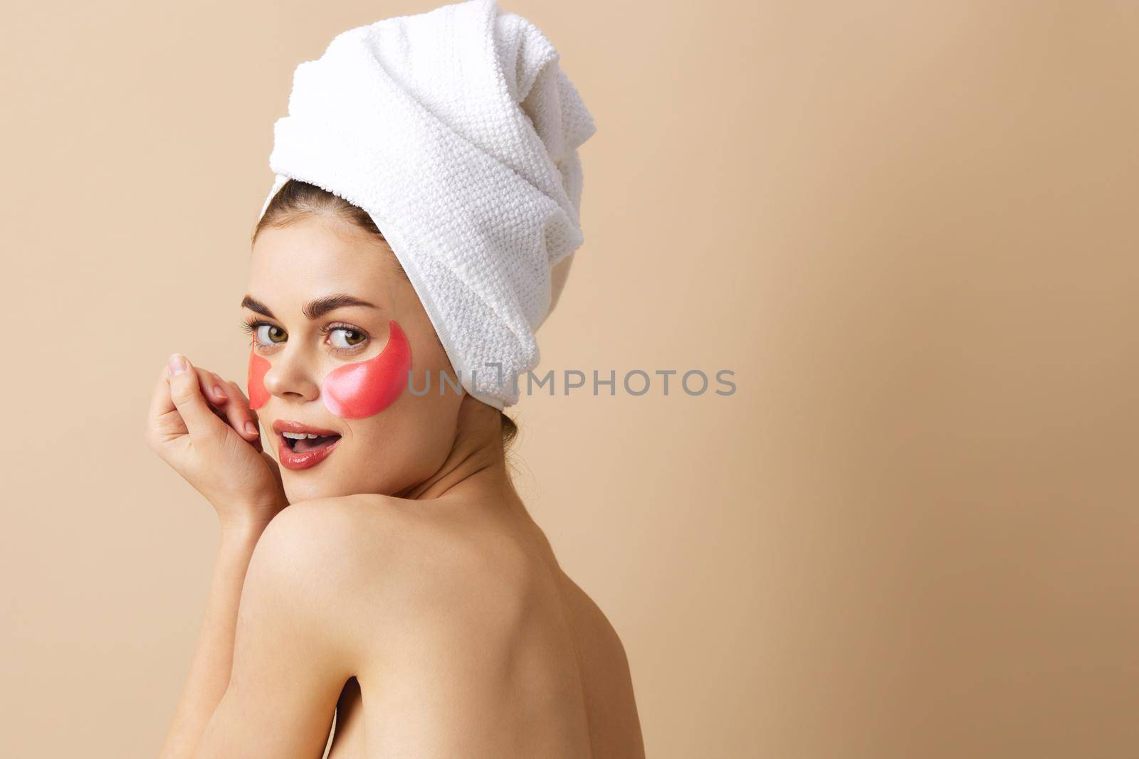 young woman pink patches on the face with a towel on the head beige background. High quality photo