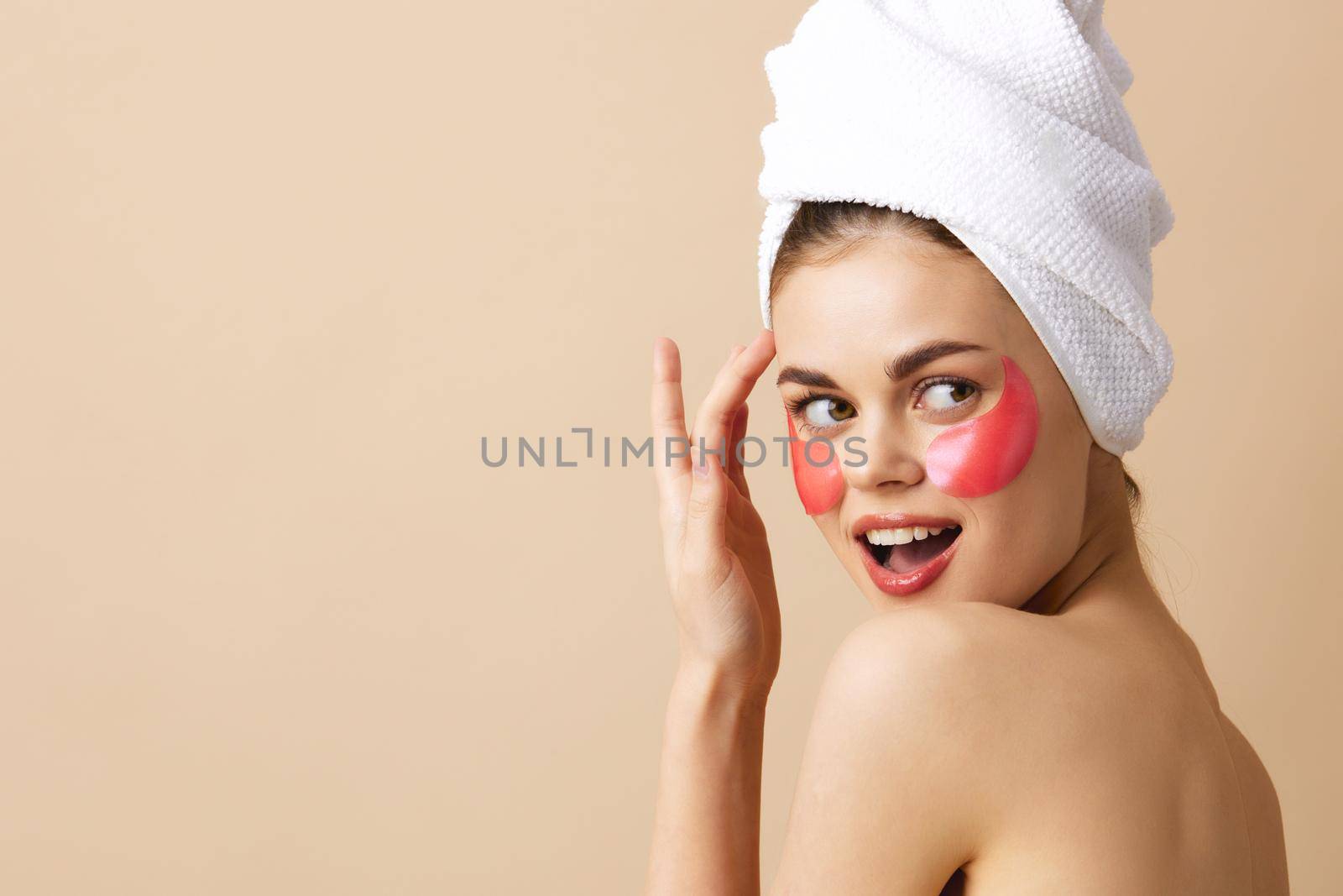 pretty woman pink patches on the face with a towel on the head beige background by SHOTPRIME