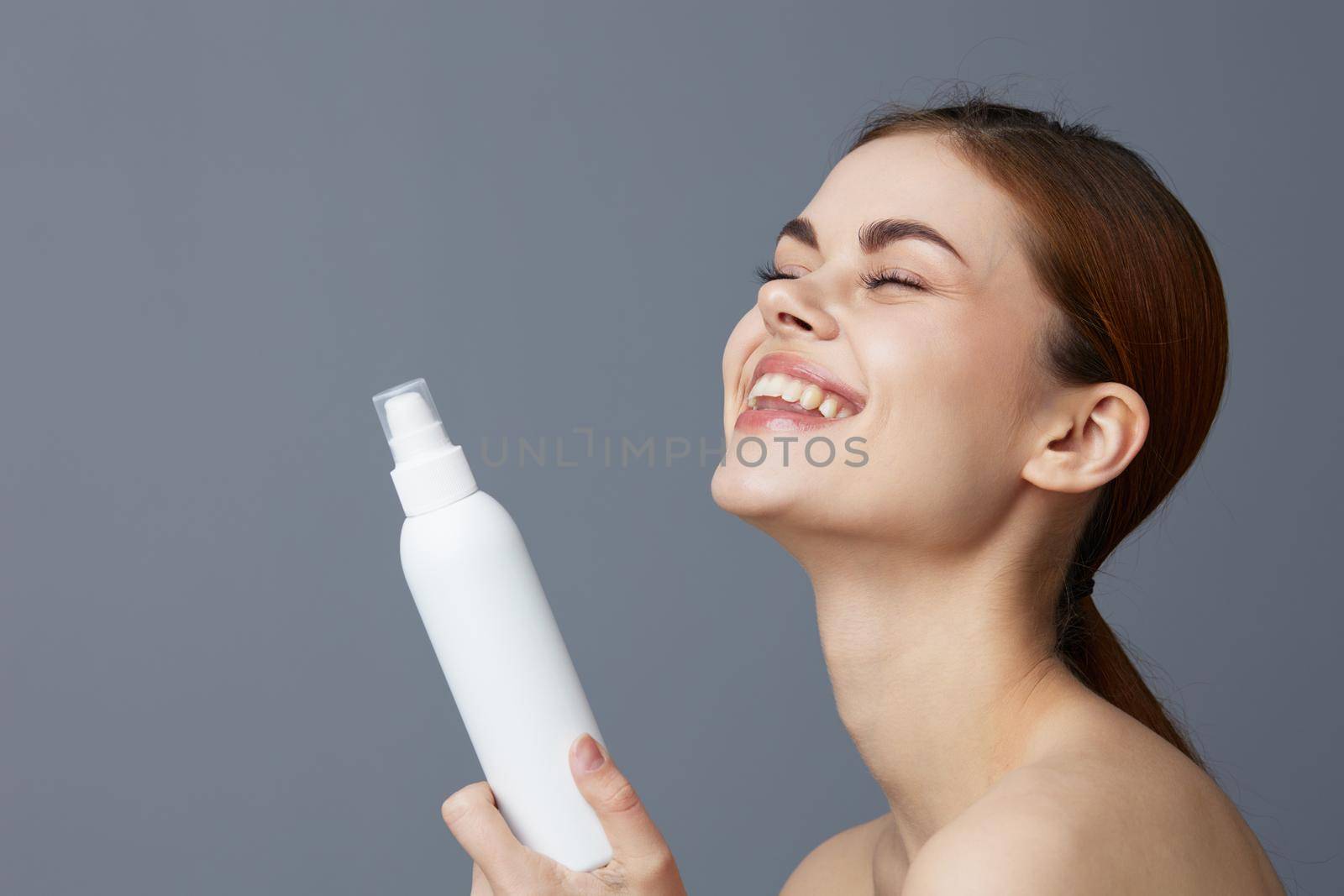 pretty woman skin care lotion with bare shoulders Gray background. High quality photo