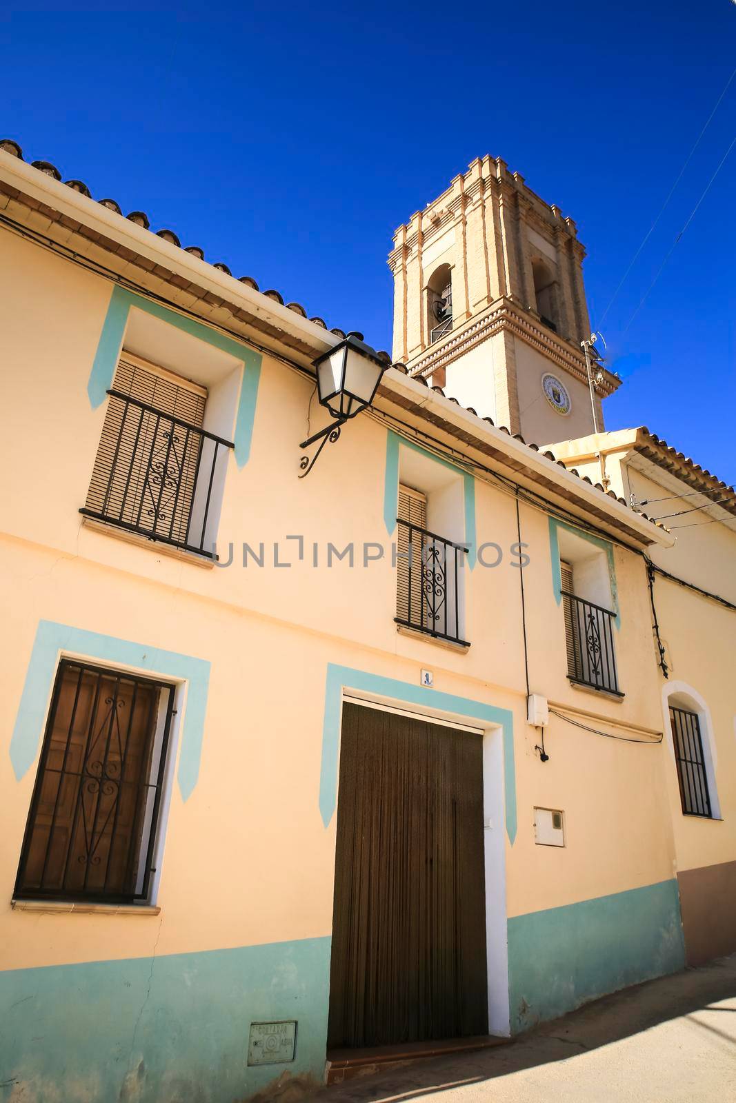 Bolulla, Alicante, Spain- February 6, 2022: Facades of Bolulla village and San Jose church tower in the background