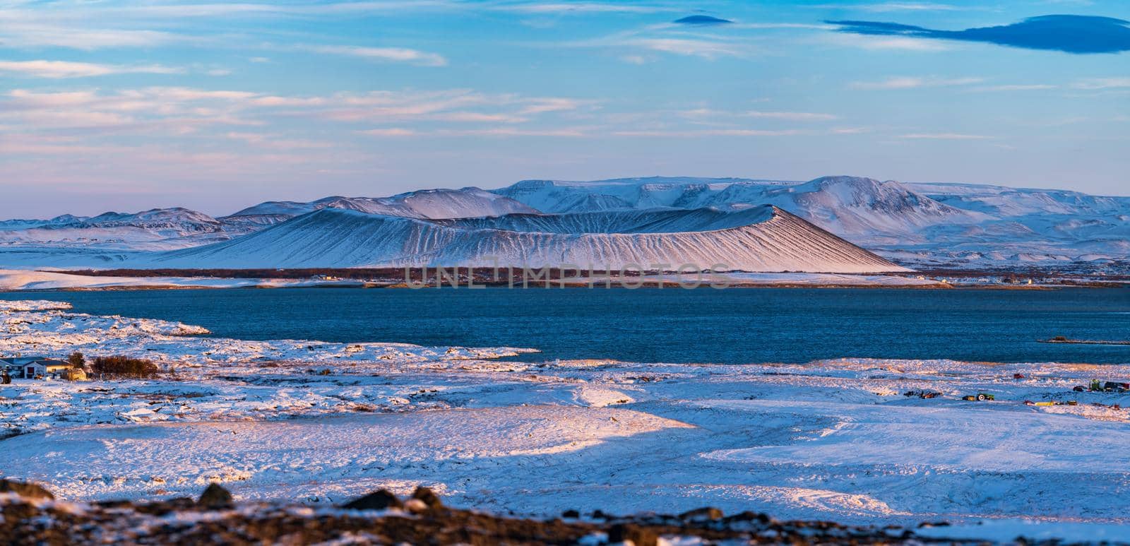Wide panorama of volcano crater over the lake covered by snow in Myvatn lake, Iceland