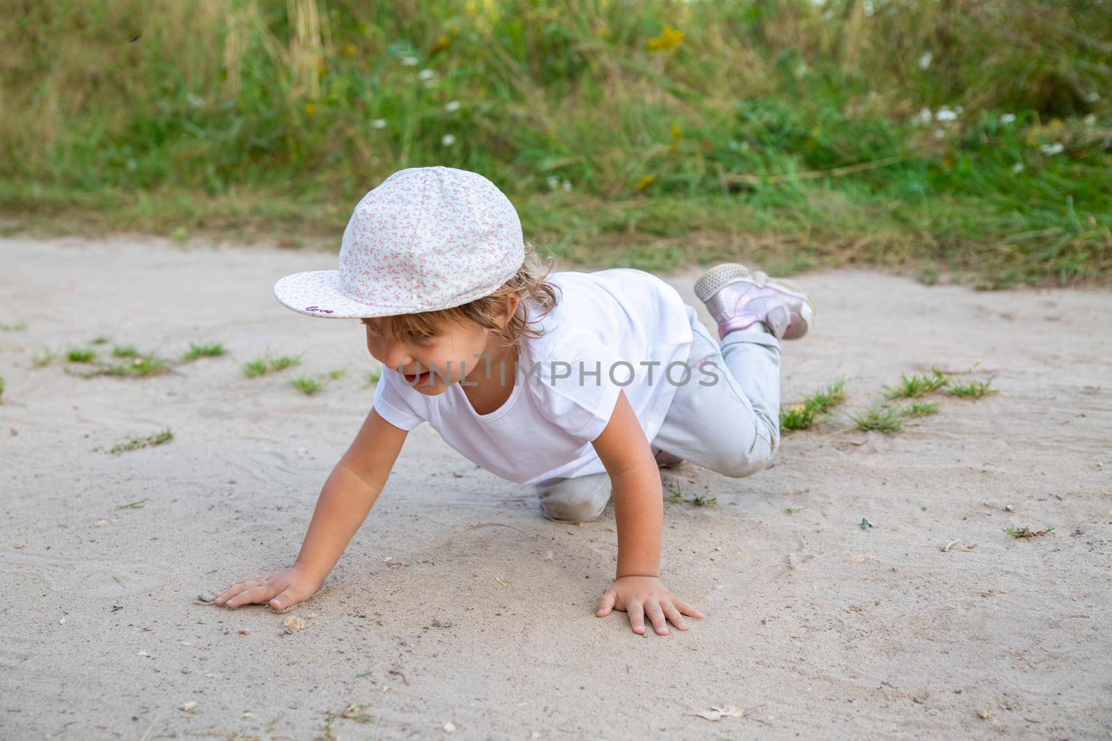 portrait of little toddler crawling in sand in counrtyside