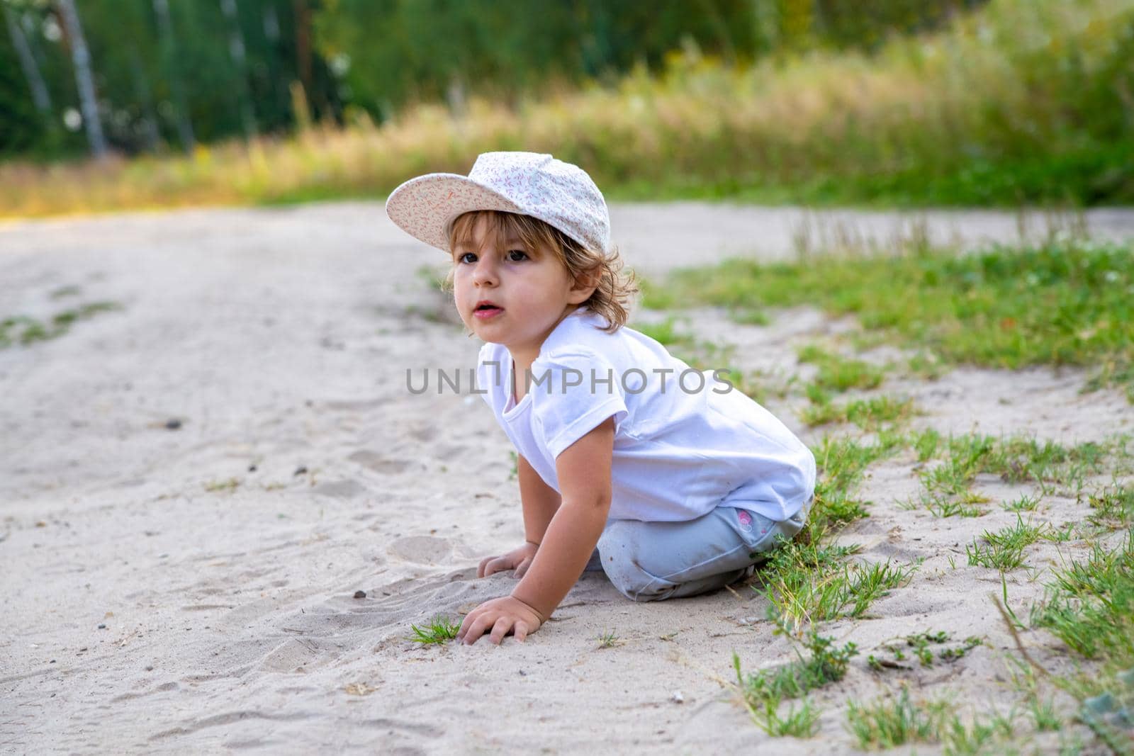 portrait of little girl sit in sand in counrtyside