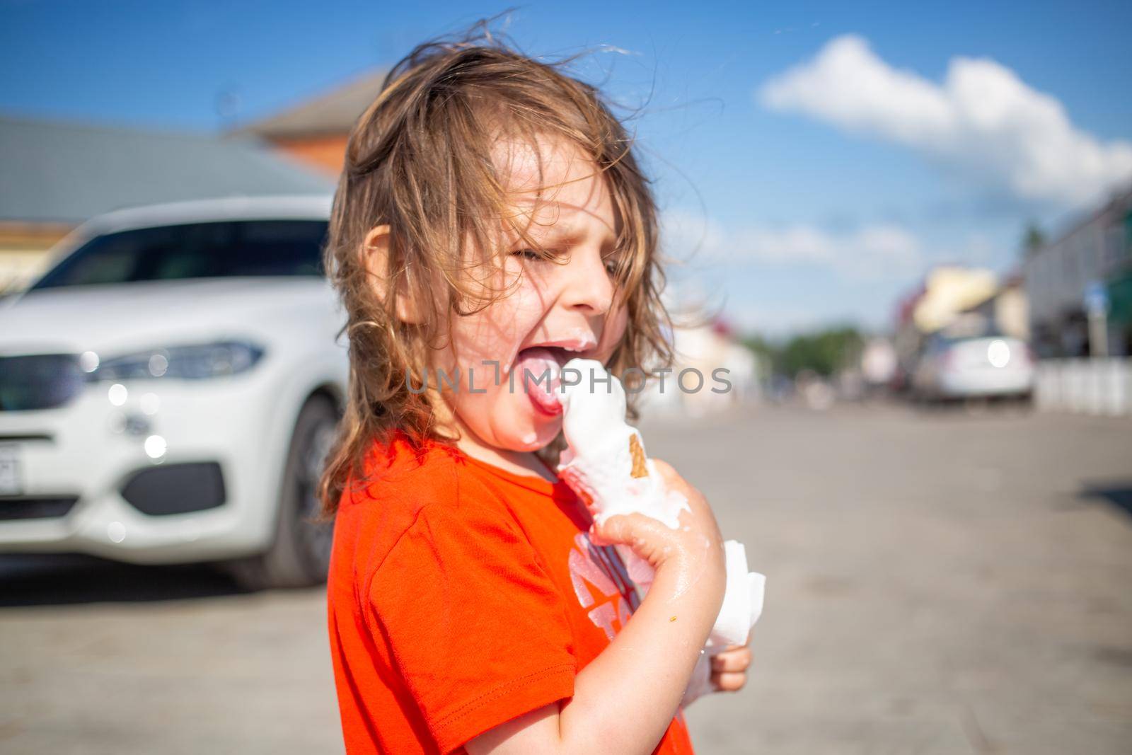 Cheerful child licking a vanilla ice cream on the beach by Mariaprovector