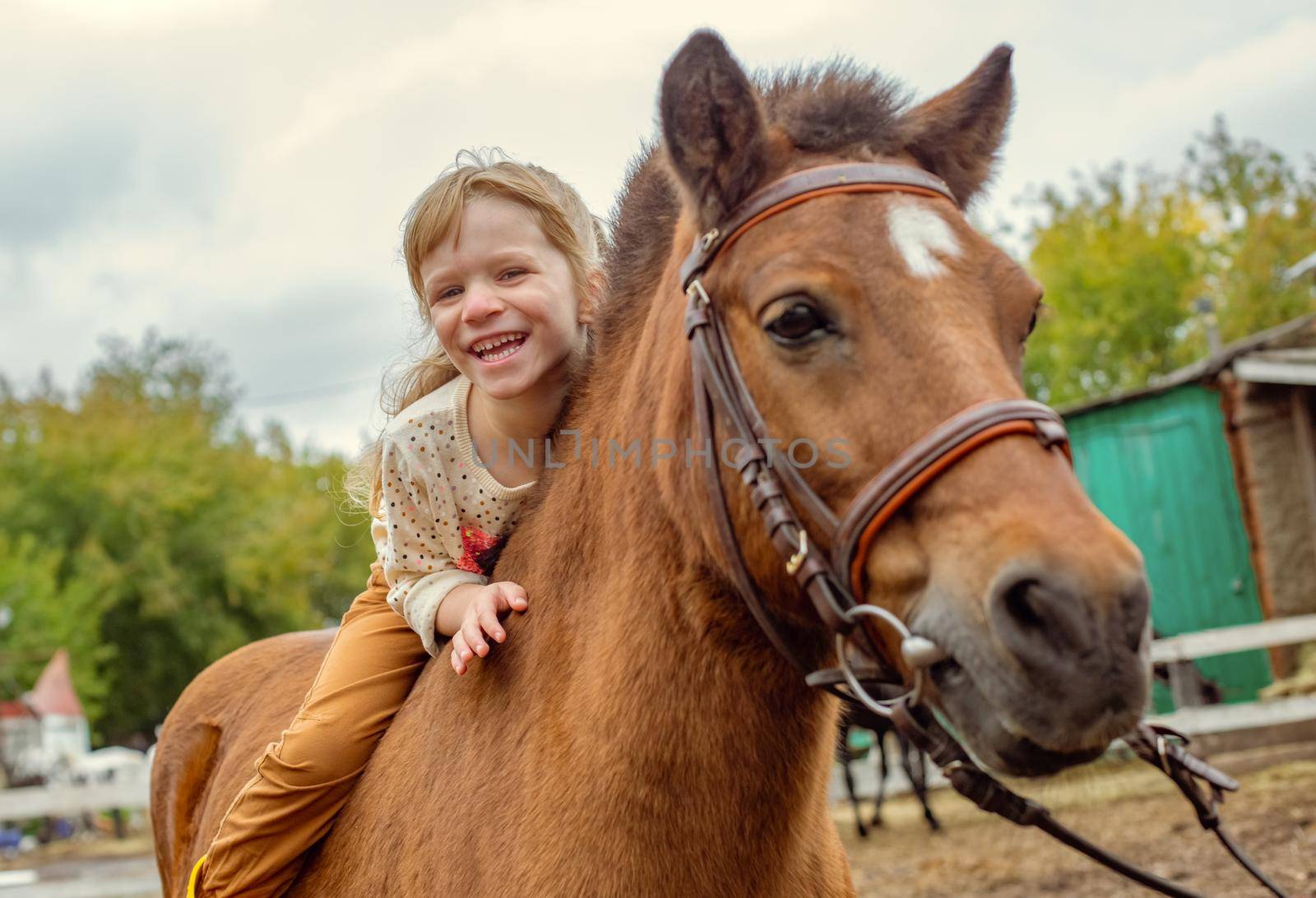 happy little girl riding pony horse bareback and laugh by Mariaprovector