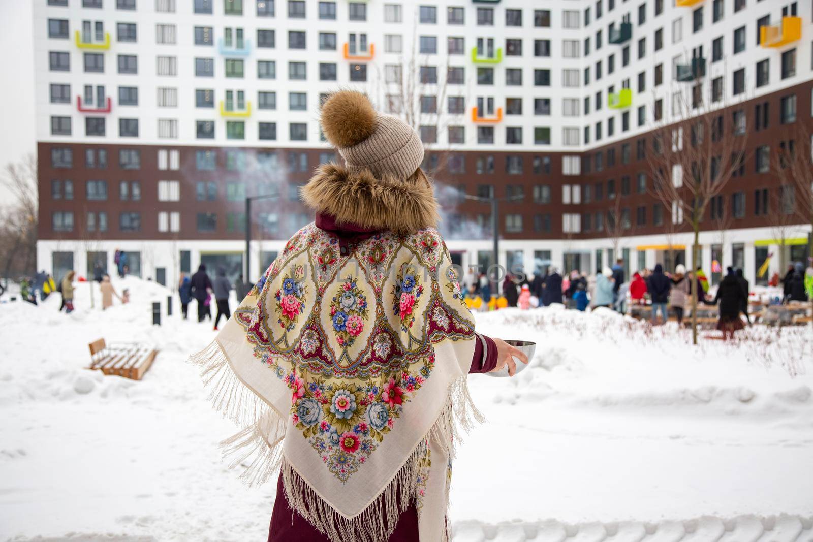 rear view of woman in traditional russian scarf at winter festival maslenitsa by Mariaprovector