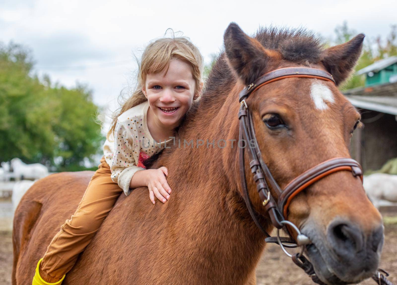 happy little girl riding pony horse bareback and laugh by Mariaprovector