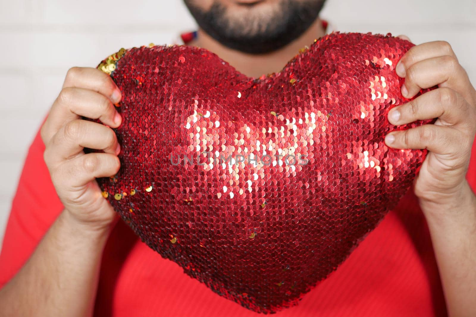 young man holding big red heart close up ,