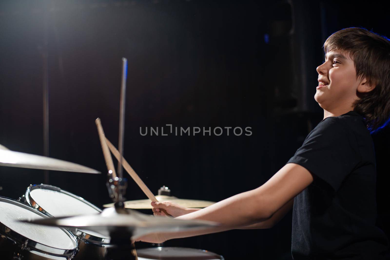 A boy plays drums in a recording studio.