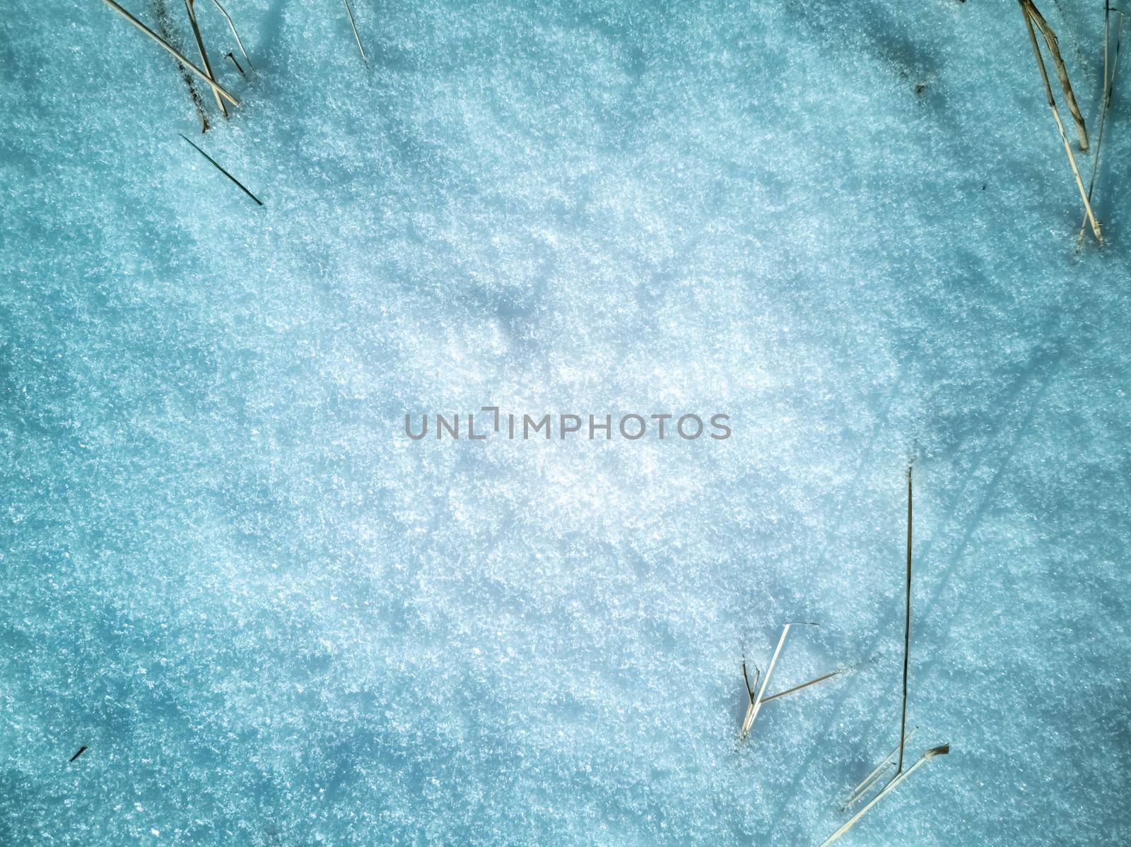 abstract natural texture of snow and dry grass. top view of snow covered field pattern