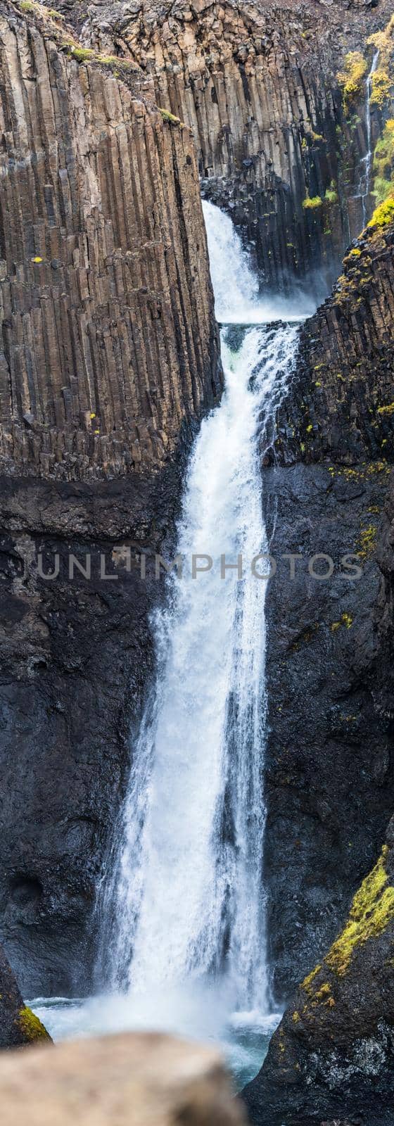 Spectacular waterfall between narrow basaltic columns path