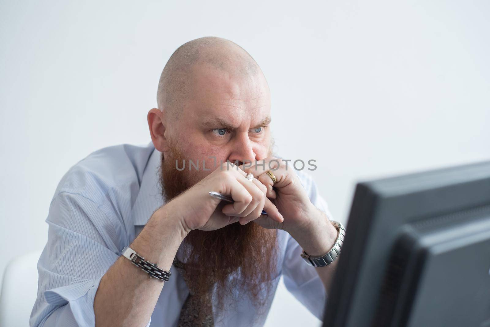 Problems for the office worker. A bald man in a white shirt sits at a desk with a computer and is stressed because of failure. A nervous breakdown