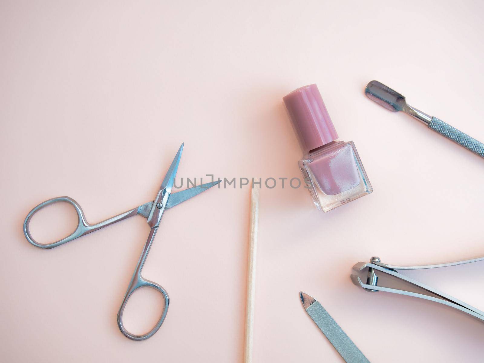 A set of cosmetic tools for manicure and pedicure on a pink background. Gel polishes, nail files, manicure scissors. photo