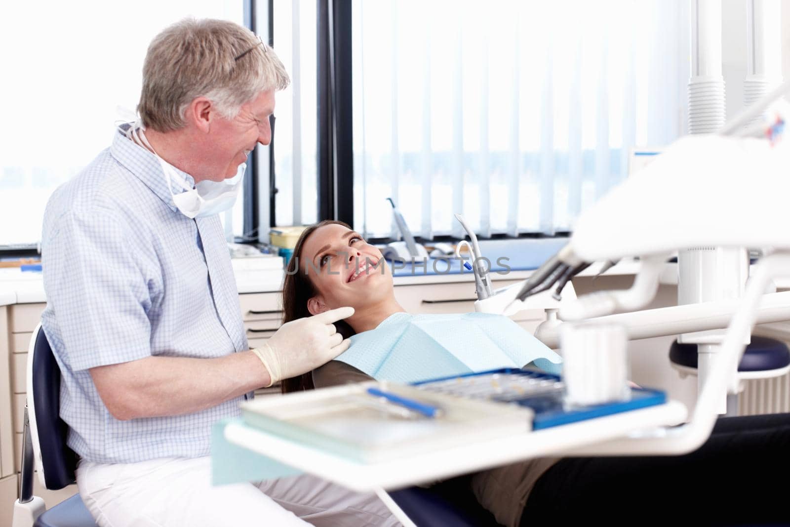 Portrait of mature doctor speaking to his patient in clinic.