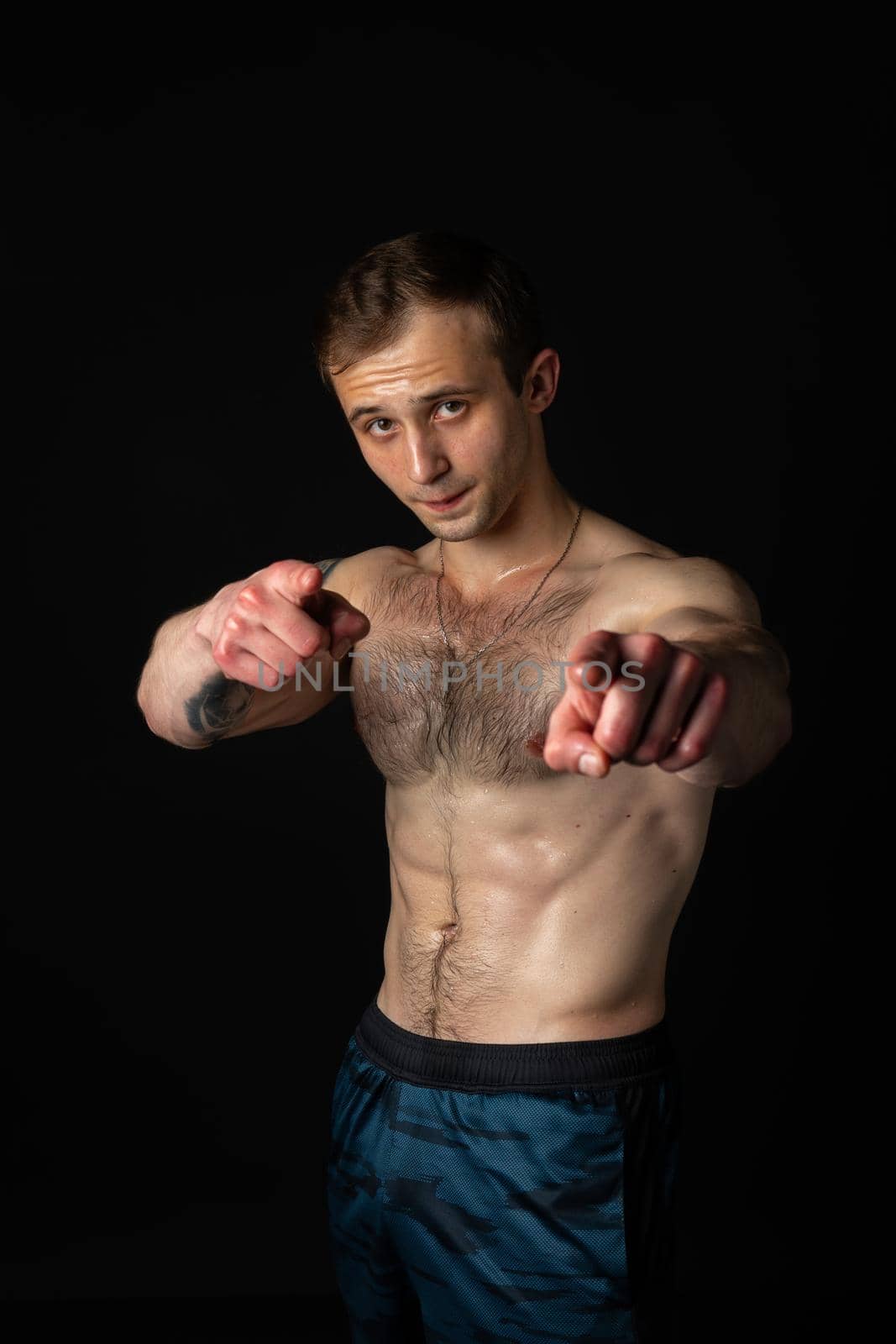 Man on black background keeps dumbbells pumped up in fitness bodybuilding sexy black, body exercise dumbbell, person pectoral. Attractive skin human fit fingers point at us