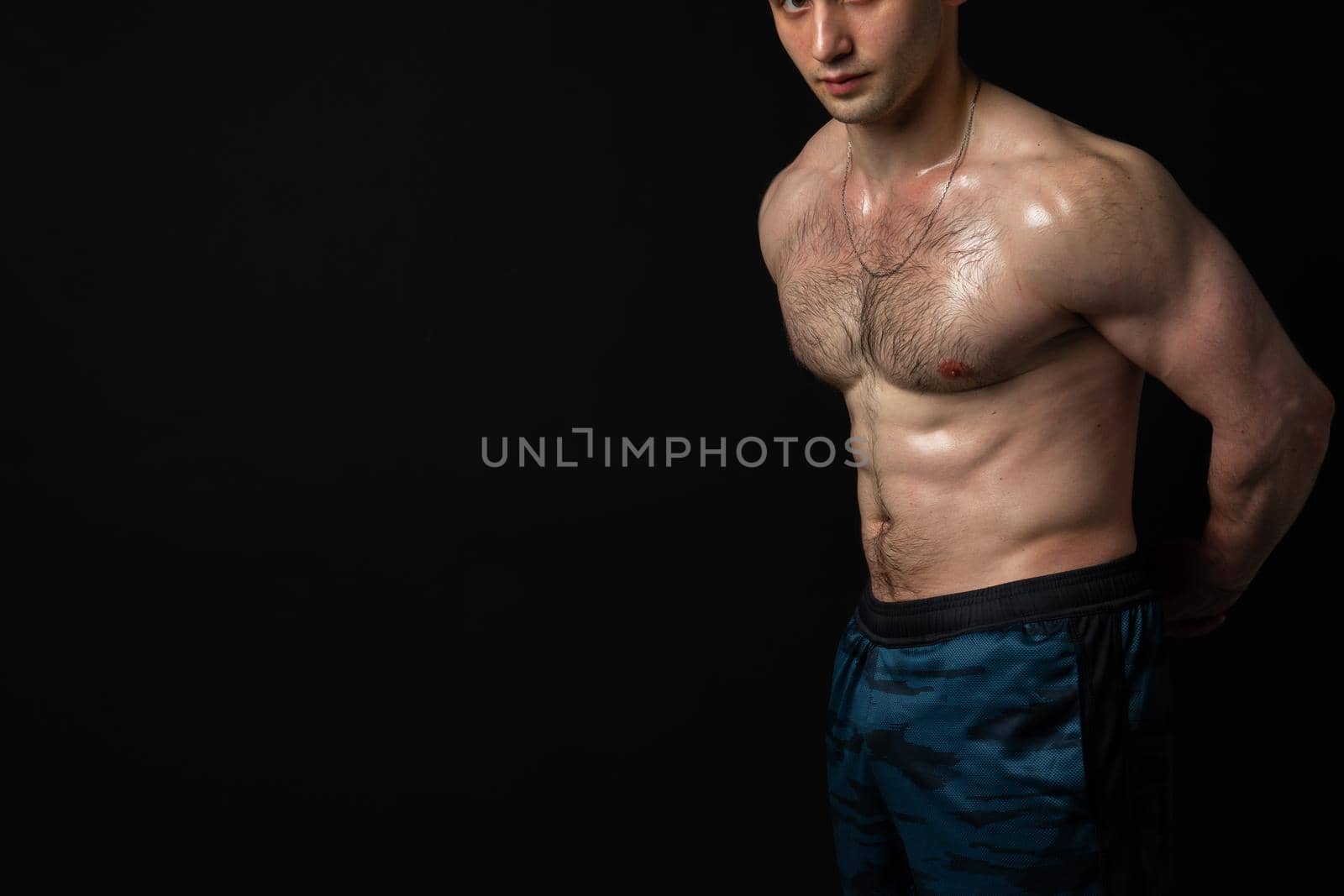 Man on black background keeps dumbbells pumped up in fitness chest weight workout dumbbell, shirtless Young adult, human fit beautiful press with hair