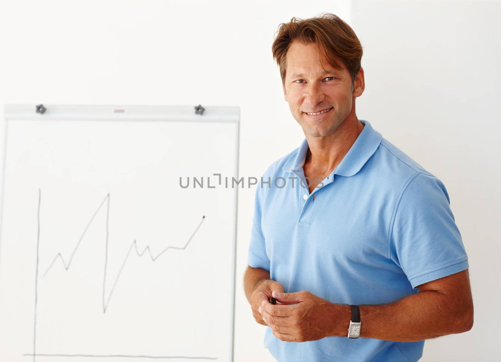 Medium shot of a mature man standing beside a whiteboard.