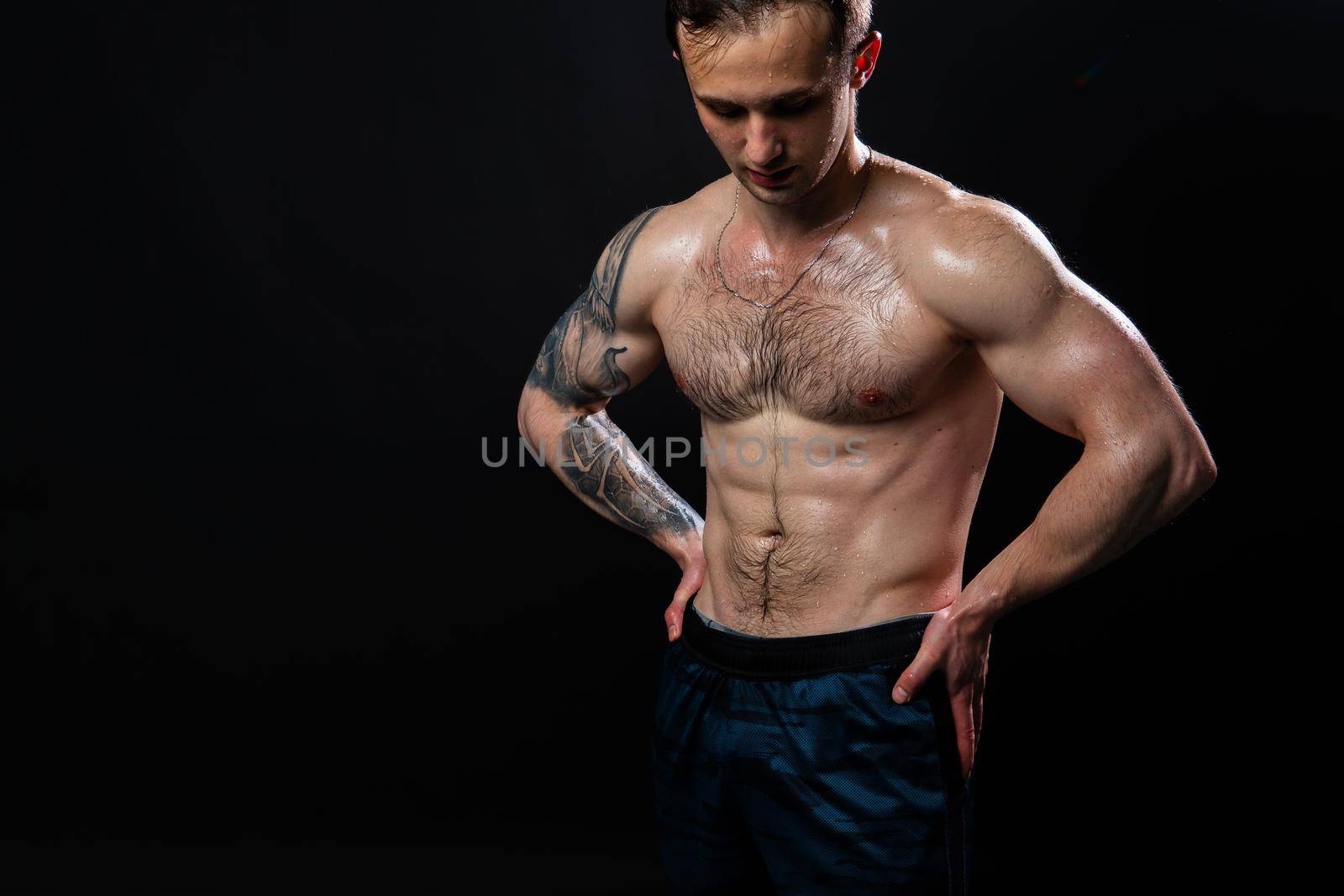 Man on black background keeps dumbbells pumped up in fitness sexy torso, athlete fitness hold powerful, shirtless lifestyle. Attractive sportive adult, one fit hands behind your back, press tense beautiful body